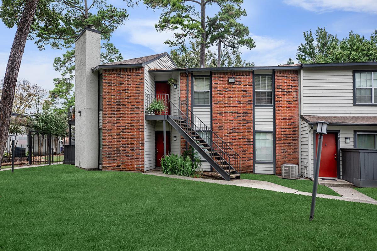 a house with a lawn in front of a brick building