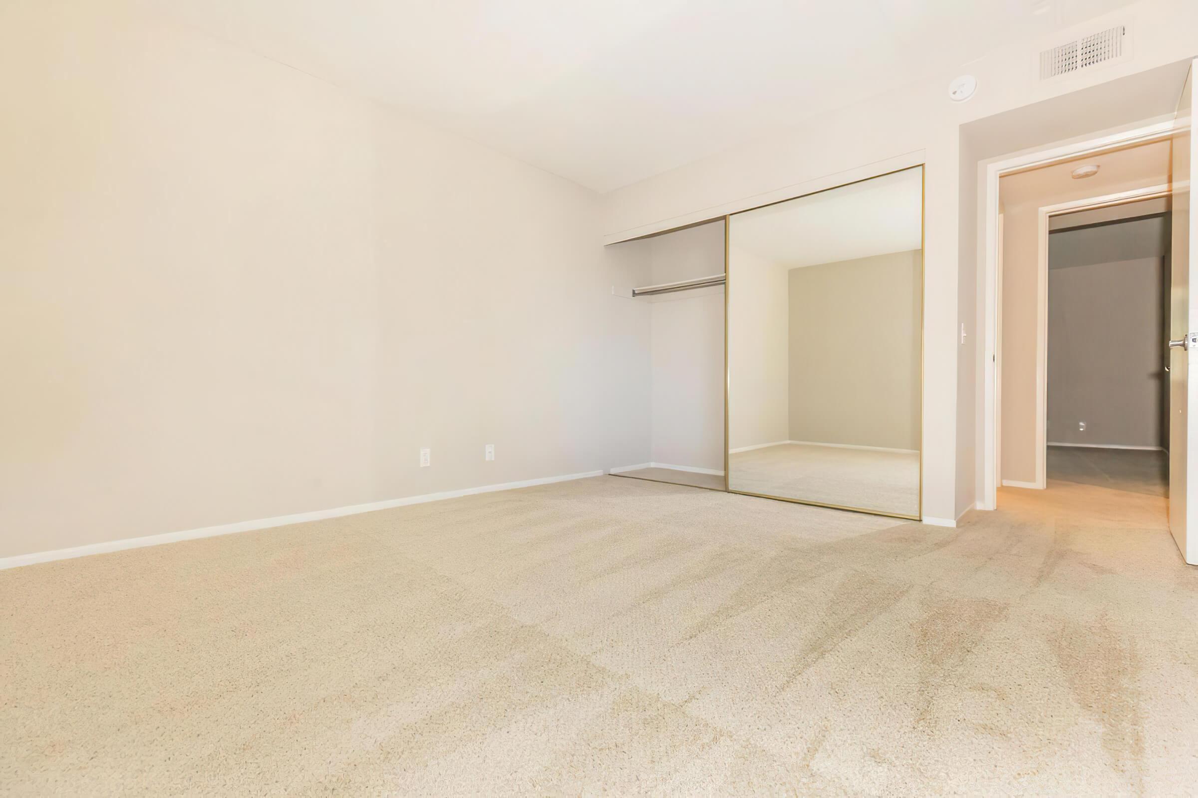Vacant bedroom with open sliding mirror glass closet door