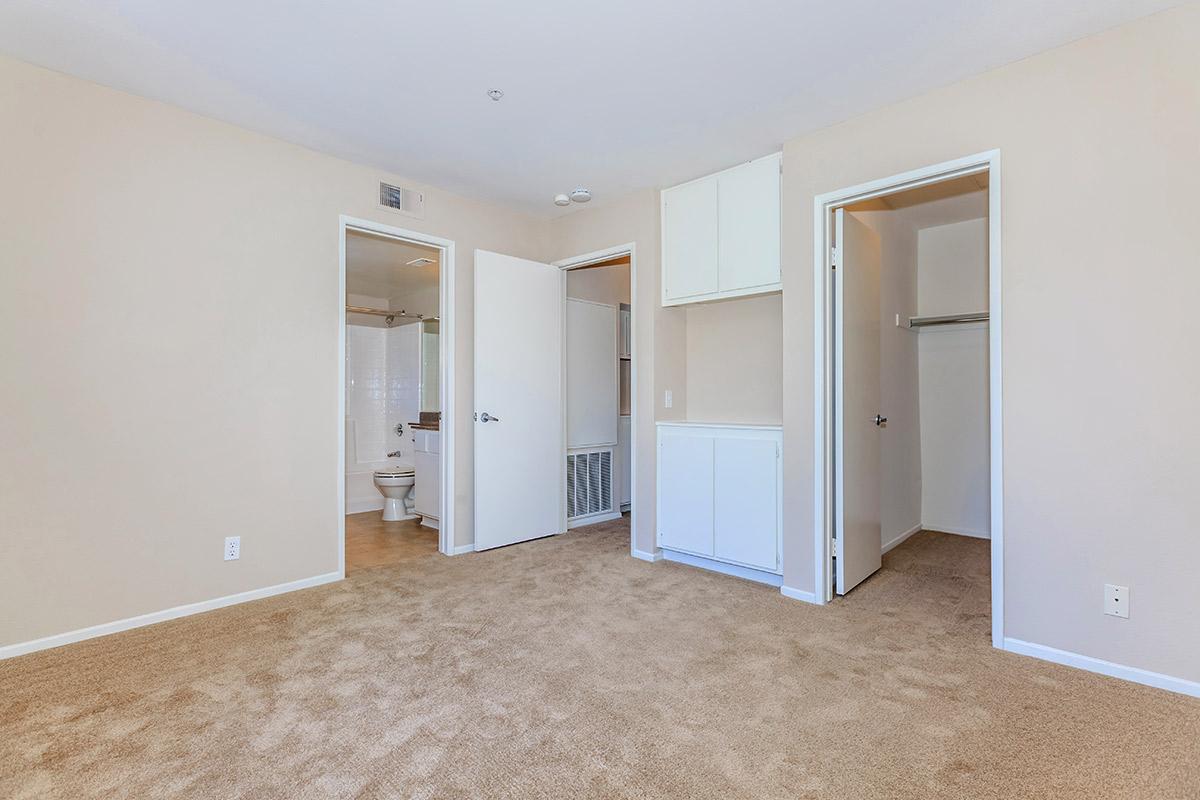 Vacant bedroom with open bathroom and closet doors