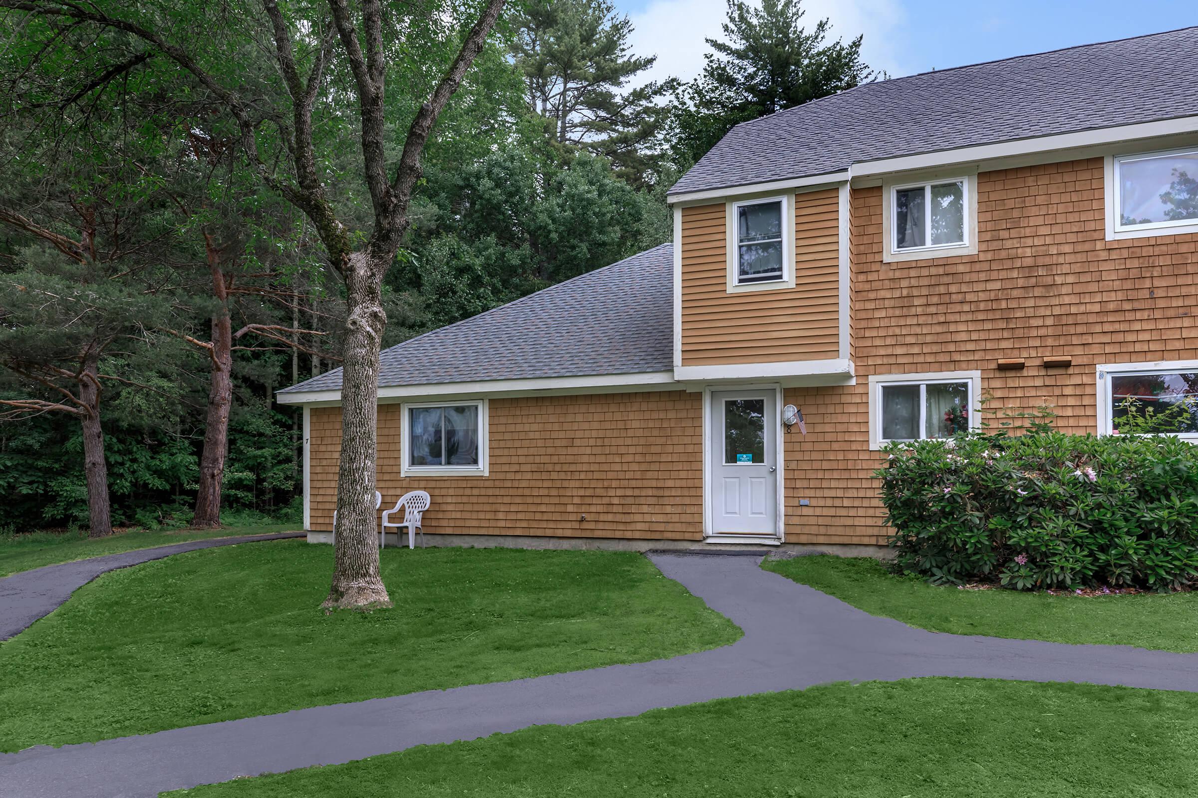 a house with a lawn in front of a brick building