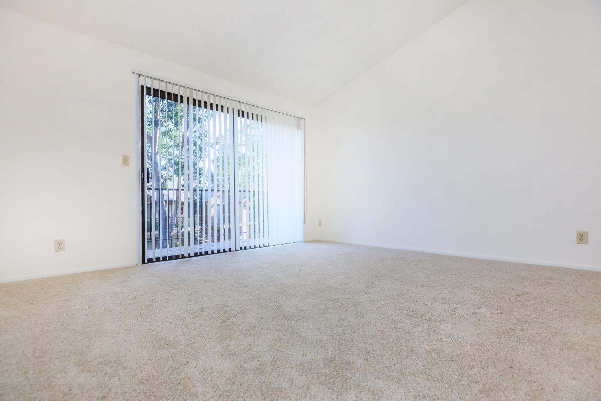 Carpeted living room with glass sliding doors to balcony