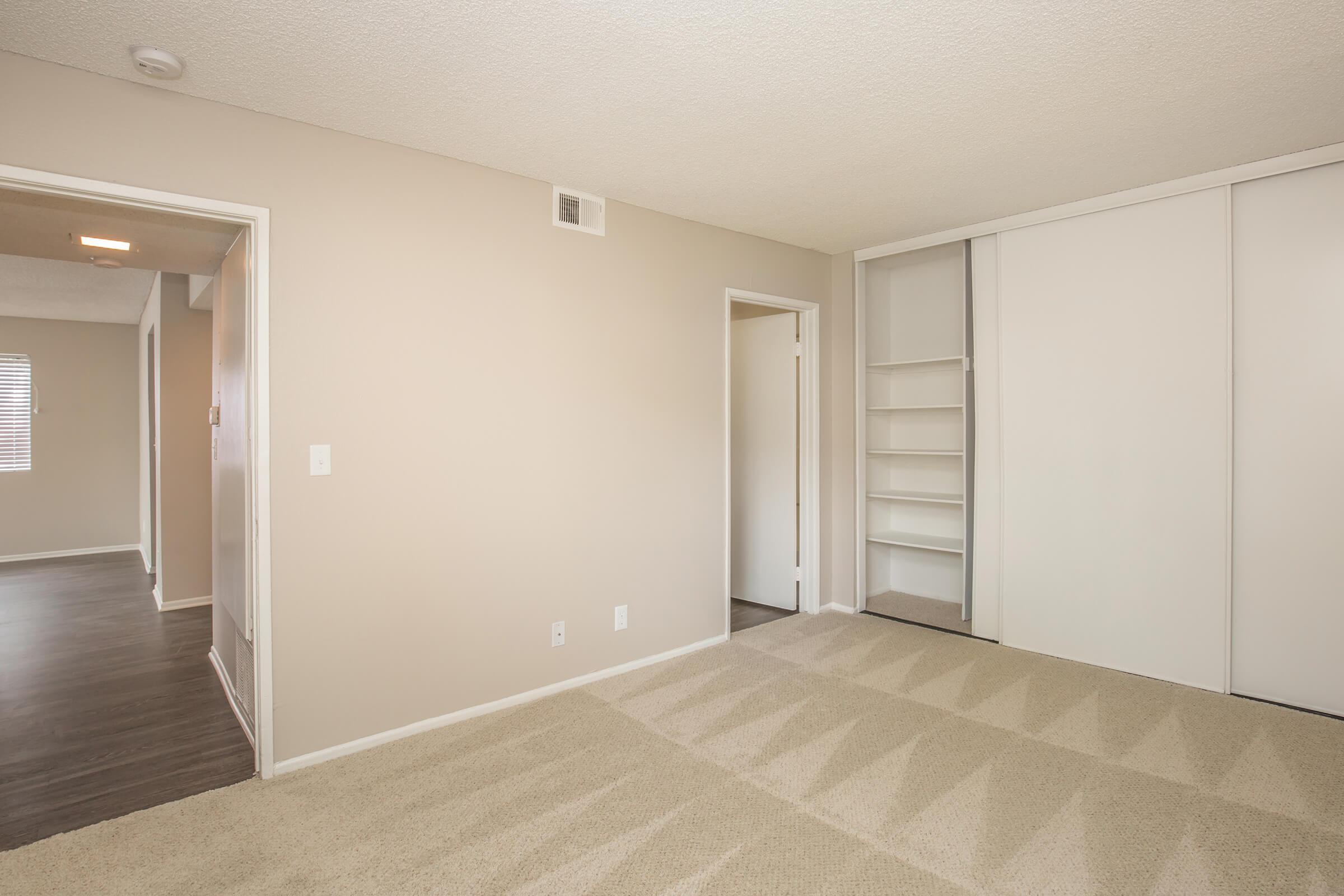 Unfurnished bedroom with open bathroom and closet doors