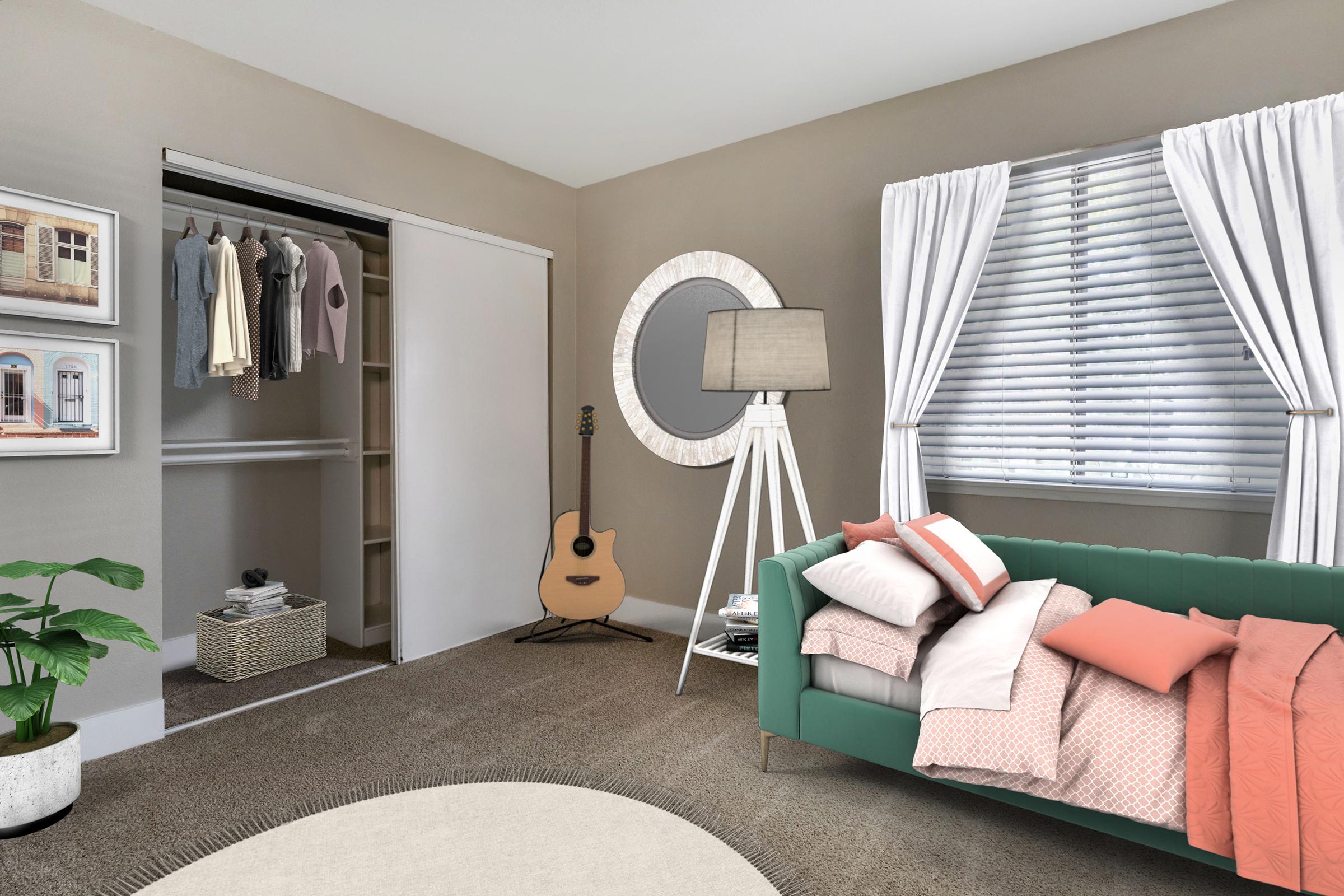 A cozy bedroom with a green sofa adorned with pillows and a blanket. A round mirror hangs on the wall beside a lamp, and there is a potted plant nearby. A closet with hanging clothes is visible, and an acoustic guitar leans against the wall. Soft natural light filters through the window with white curtains.