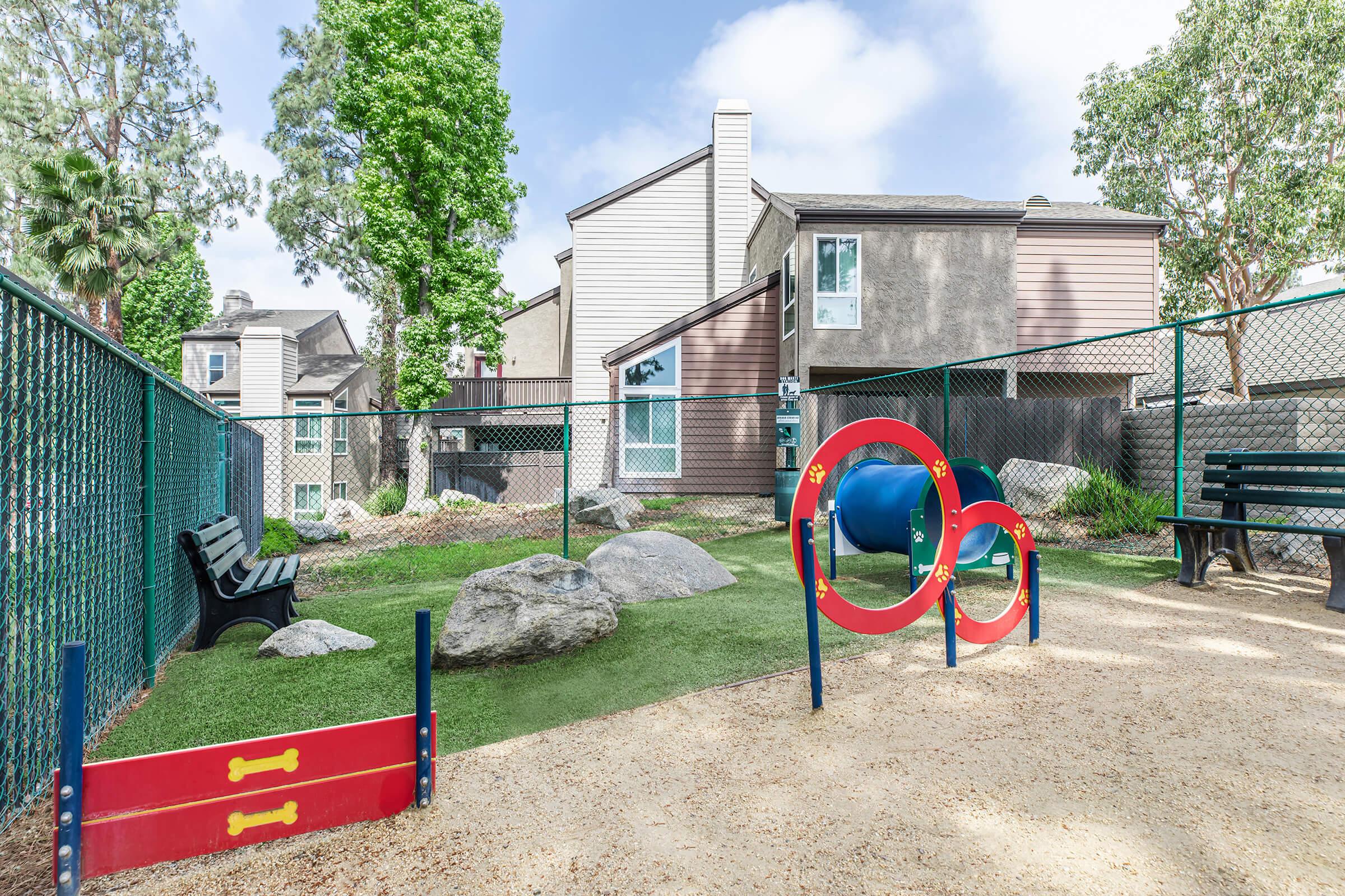 Two-Bedroom Luxury Apartments In Riverside, CA - Canyon Crest Views - Dog Park With Agility Obstacles, Grass, Benches, Dirt, Waste Area, And Rocks