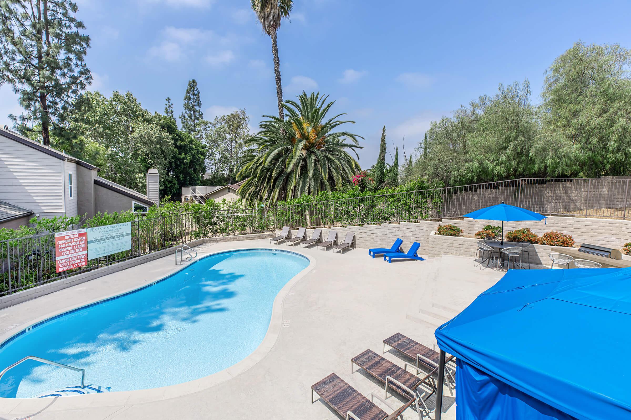 3-Bedroom Luxury Apartments In Riverside, CA - Canyon Crest Views - Shimmering Swimming Pool With Lounge Chairs, Umbrellas,Tables, And A Barbecue Area