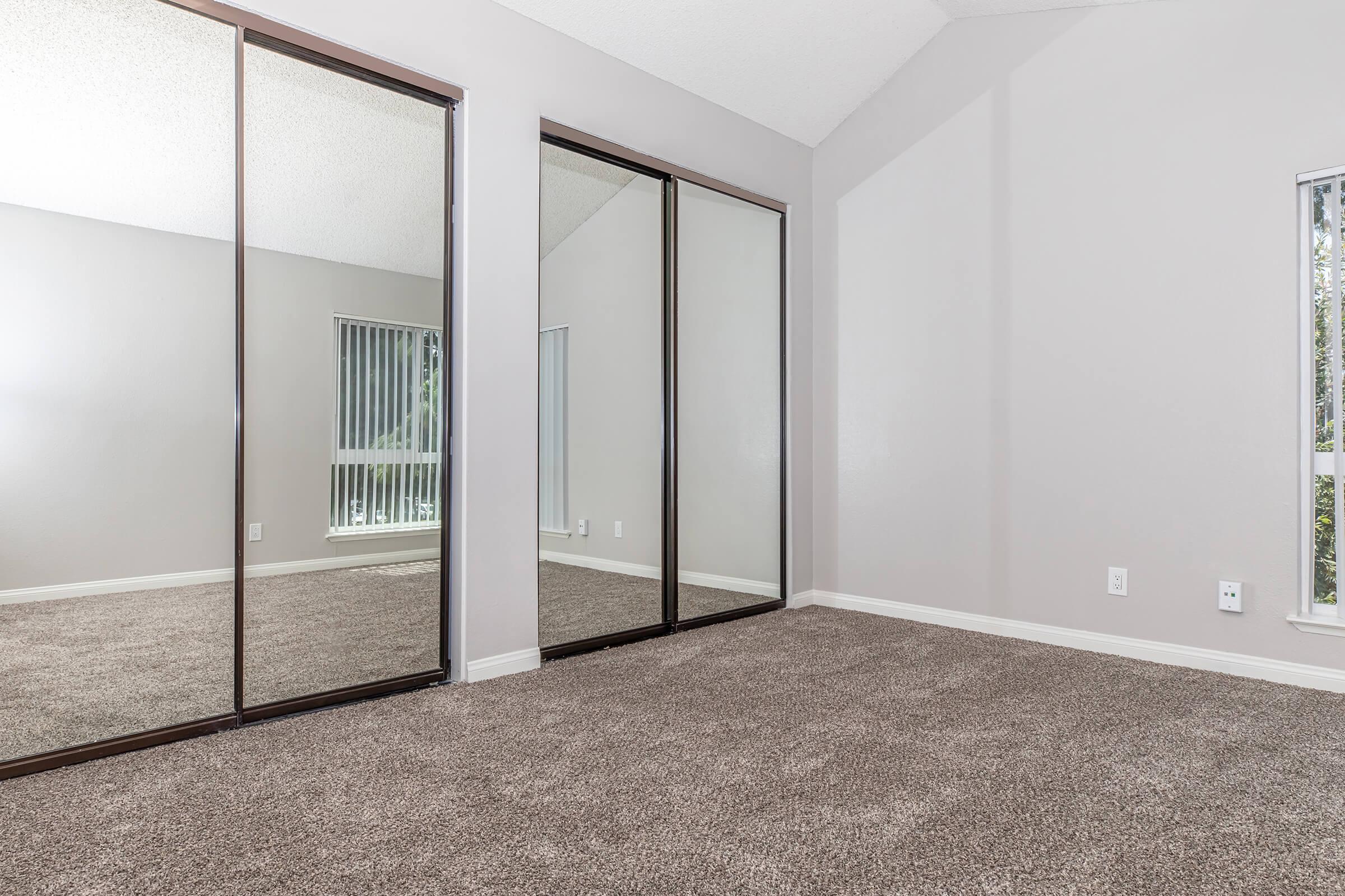 Luxury Apartments Near University of California Riverside - Canyon Crest Views - Cozy Bedroom With Plush Carpet Flooring, Two Closets With Mirror Sliding Doors, And A Window For Natural Light