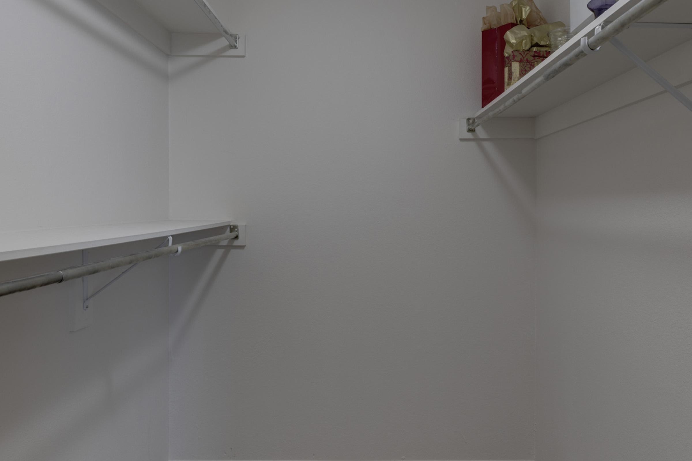 A clean, empty pantry with white shelves. Some decorative bags and containers are placed on the right side. The walls are painted white, creating a bright and minimalist appearance.