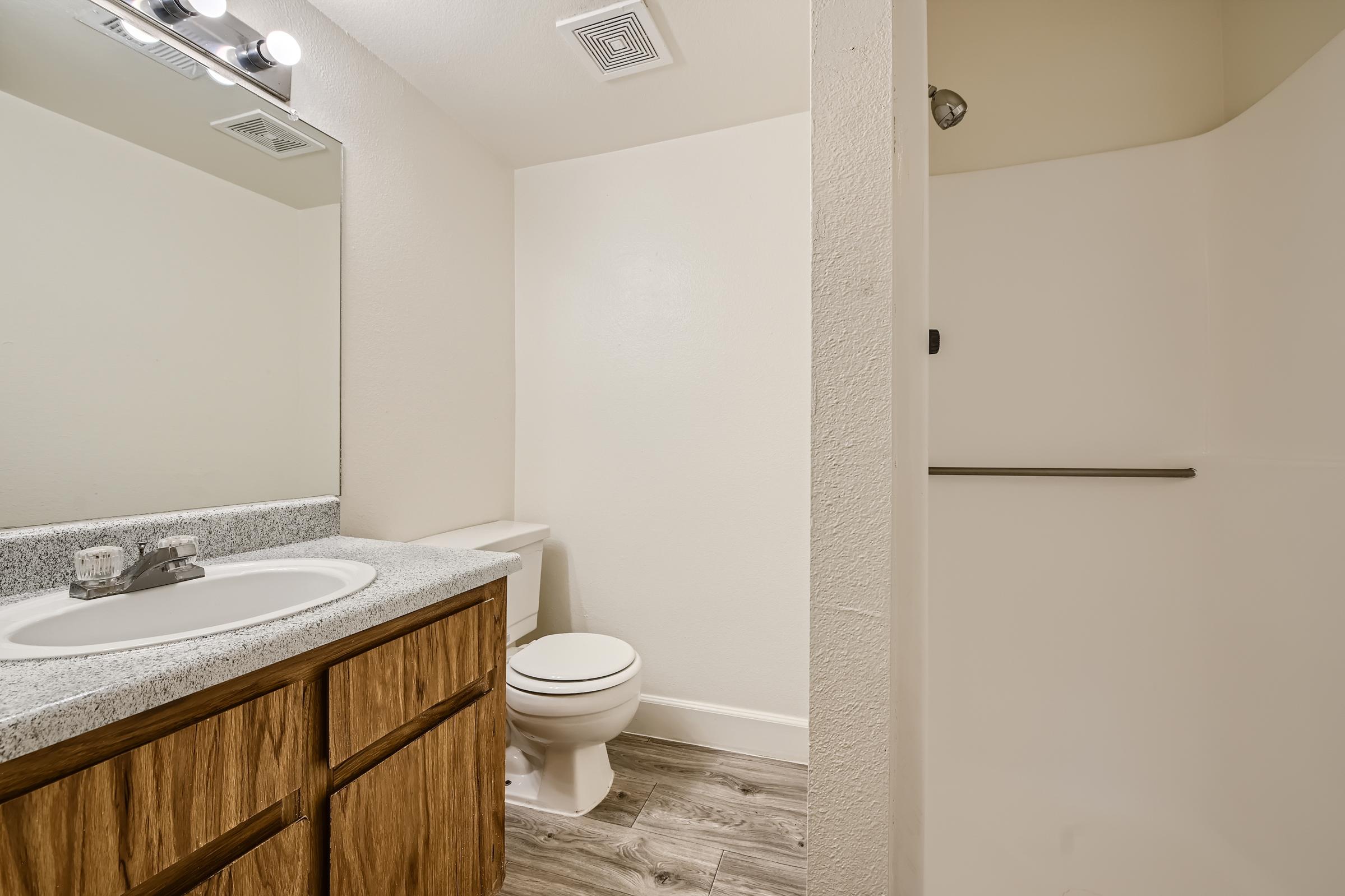 White apartment bathroom with a sink and a mirror and toilet