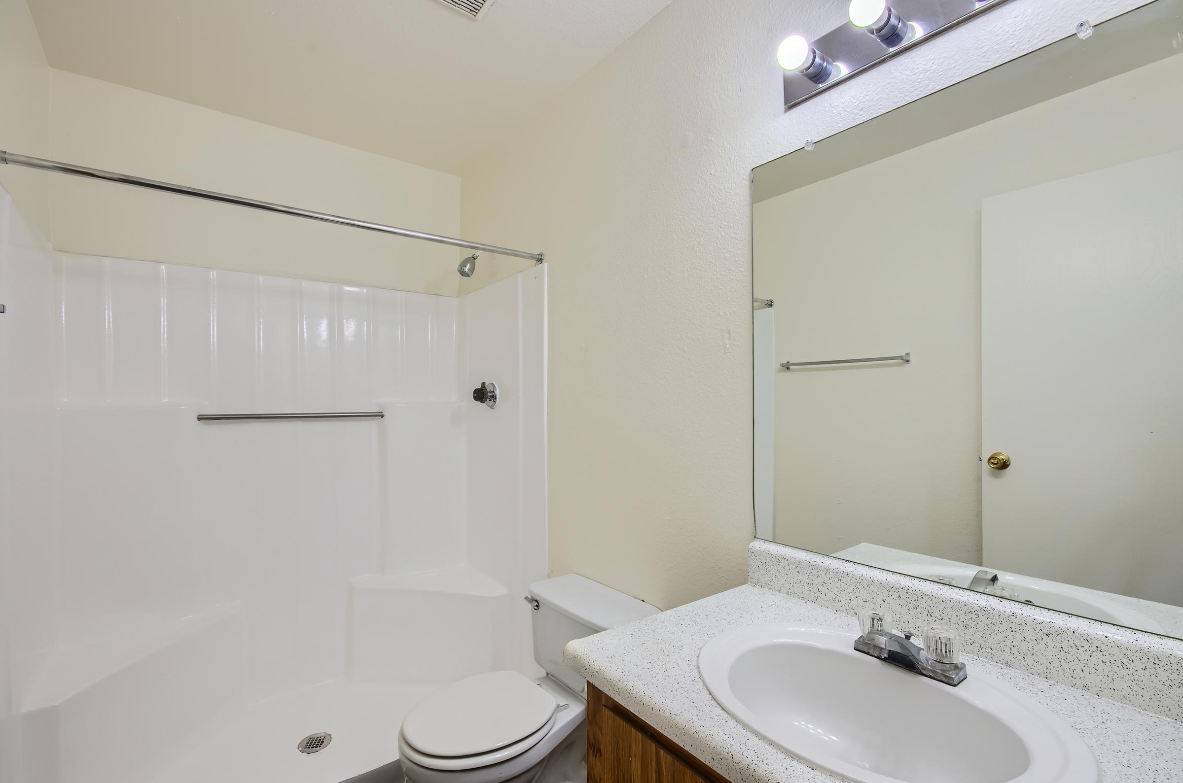 Mesa apartment bathroom with a toilet, tub, sink, and a mirror