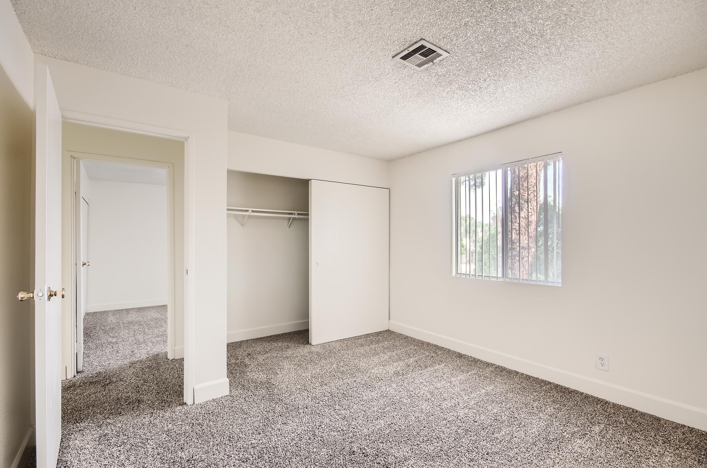 Mesa, AZ apartment carpeted bedroom with a window, door and open closet with a sliding door