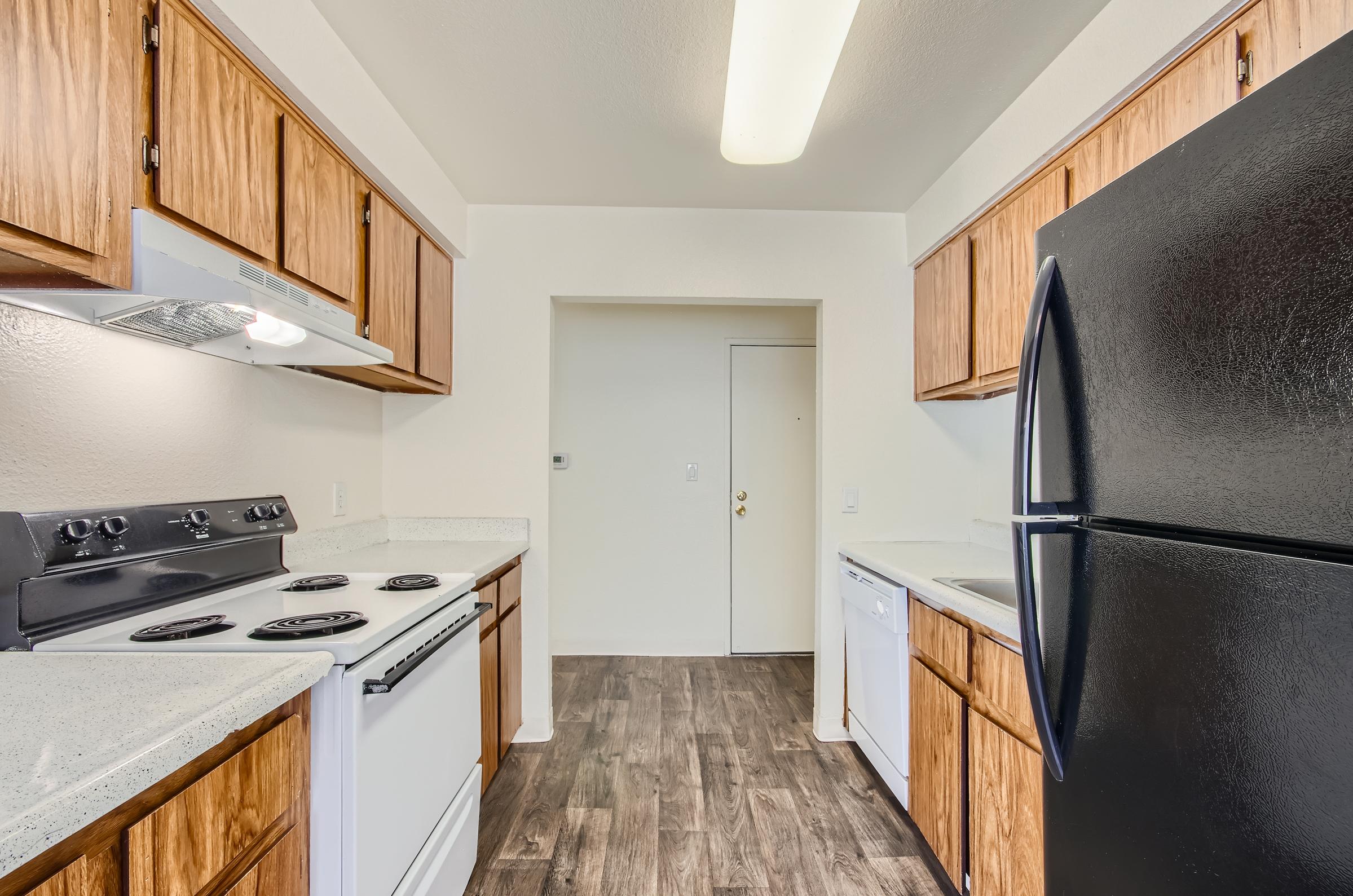 Retro Mesa apartment kitchen with wooden cabinets, black refrigerator and white appliances