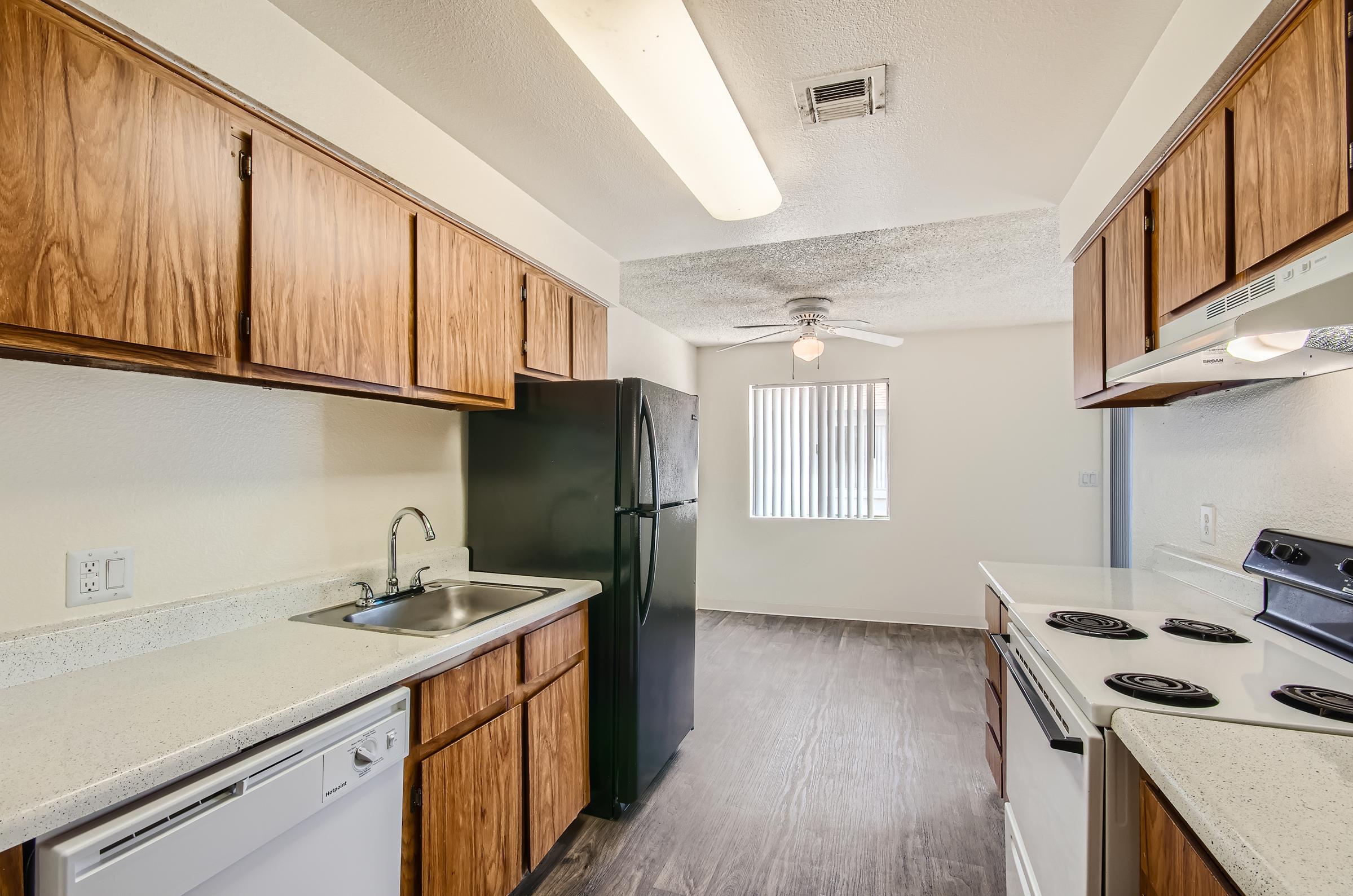 Retro Mesa, AZ apartment kitchen with wooden cabinets, black refrigerator and a sink