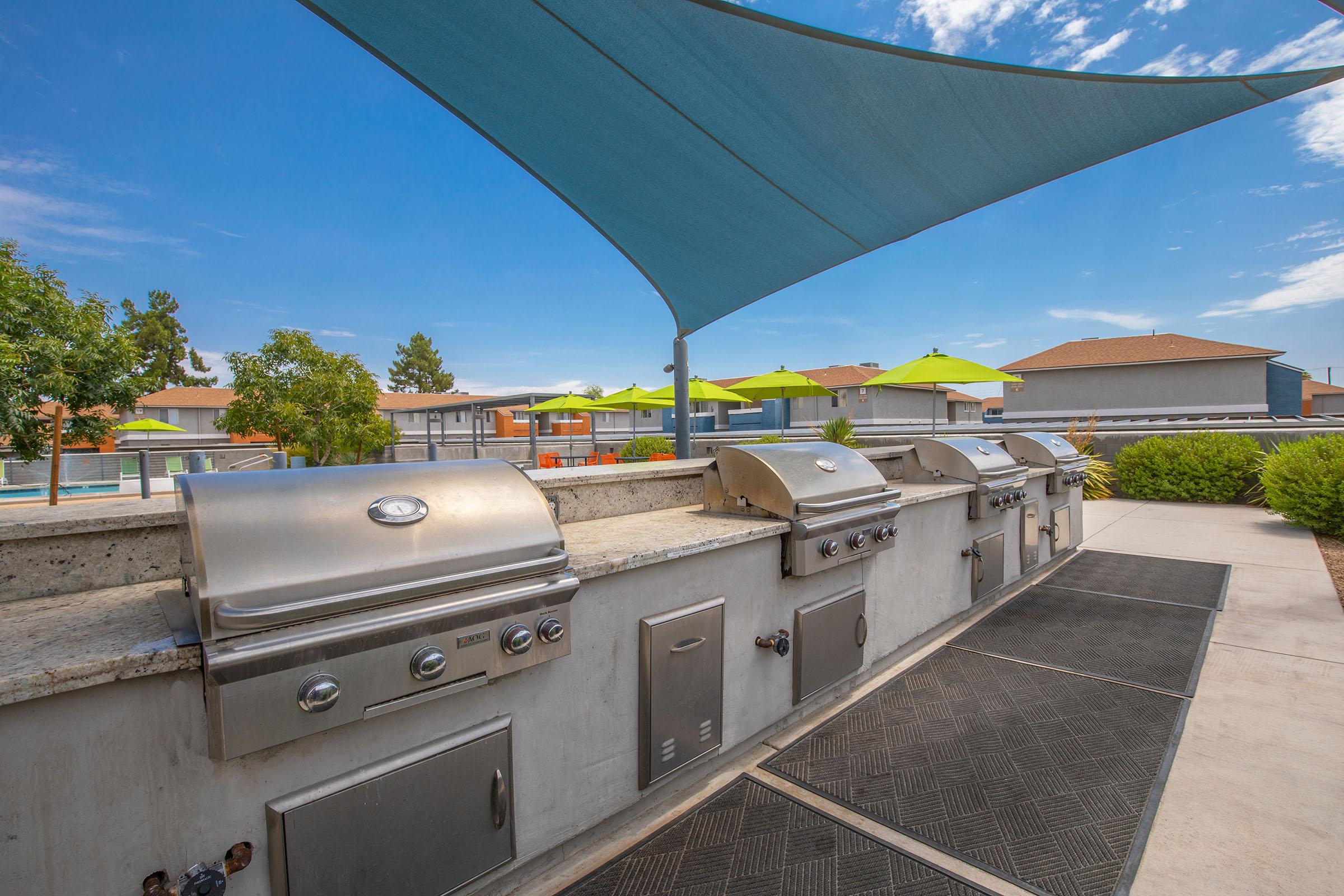 Outdoor patio bar top with 4 stainless steel grills and sunshade cover