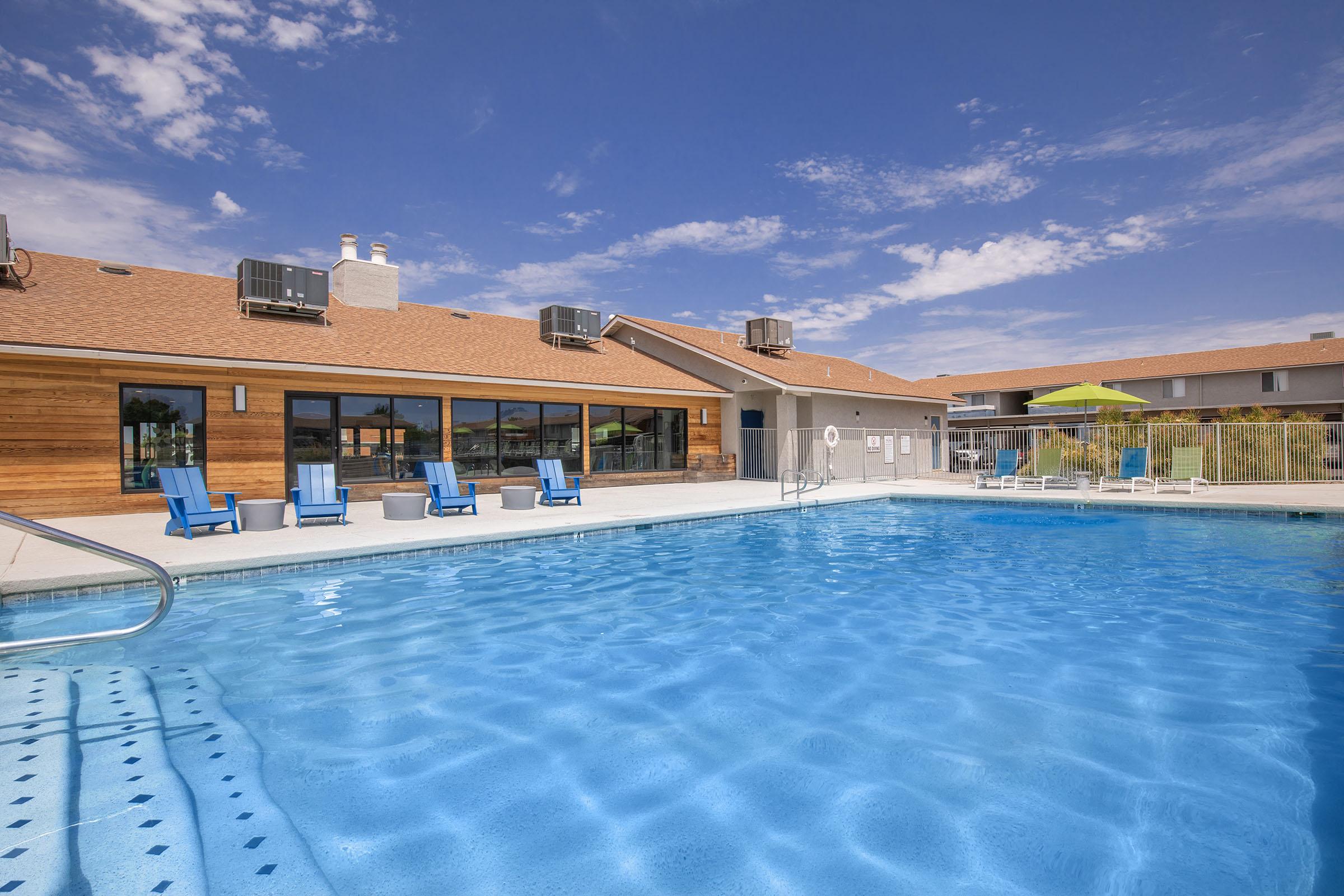Large blue sparkling resort-style pool with sunbathing chairs at Rise at the District Mesa, AZ apartments
