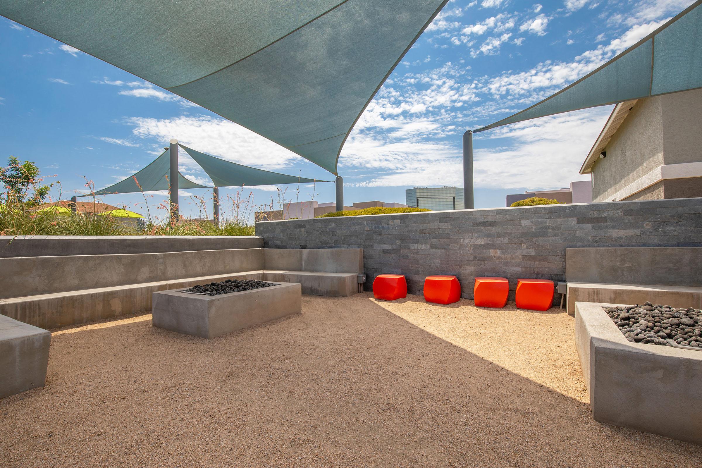 Outdoor patio Rise at the District Mesa apartments with sun shade coverings and large fire pits
