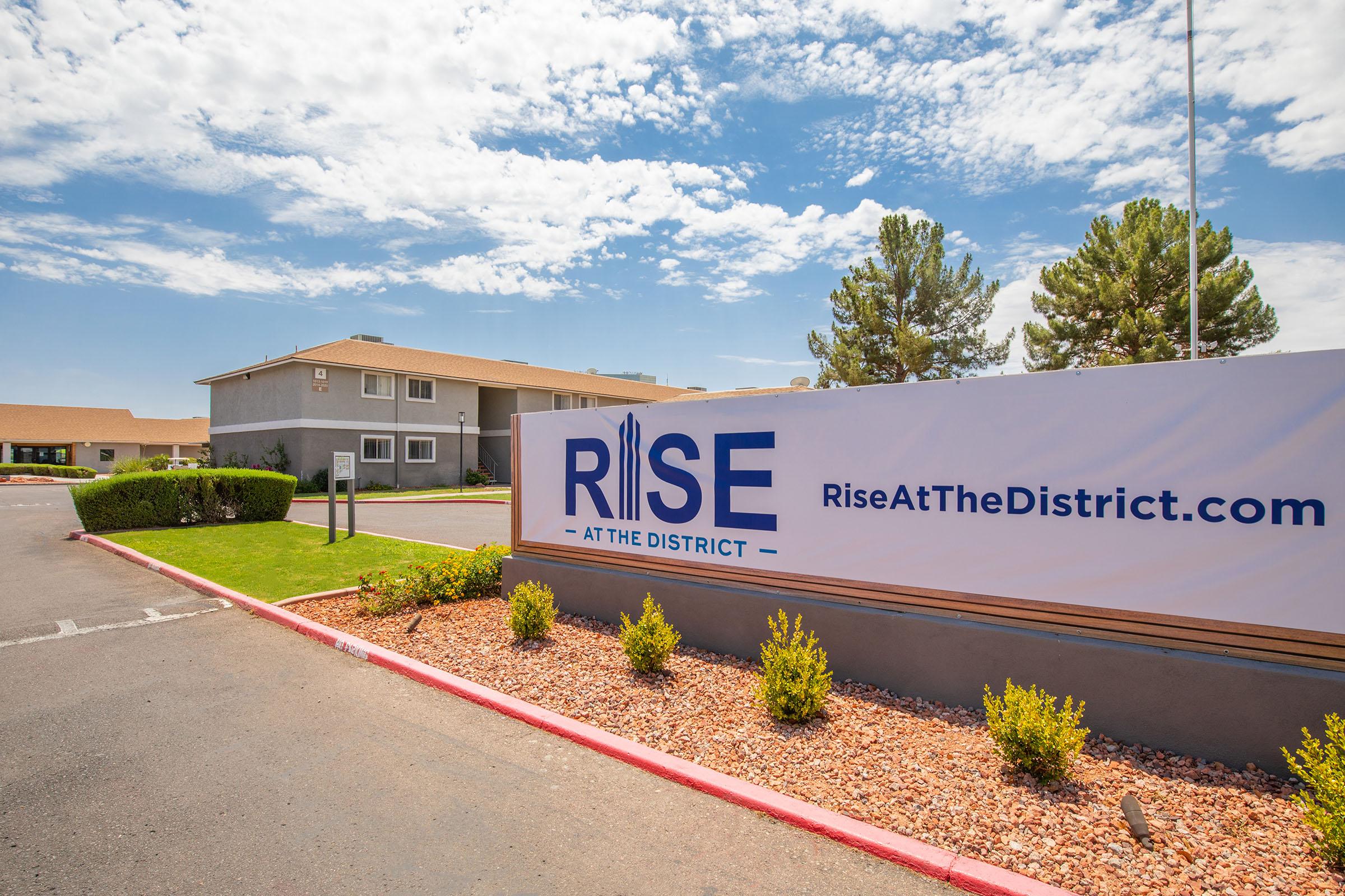 Outdoor Rise at The District welcome sign in front of Mesa, AZ apartment buildings
