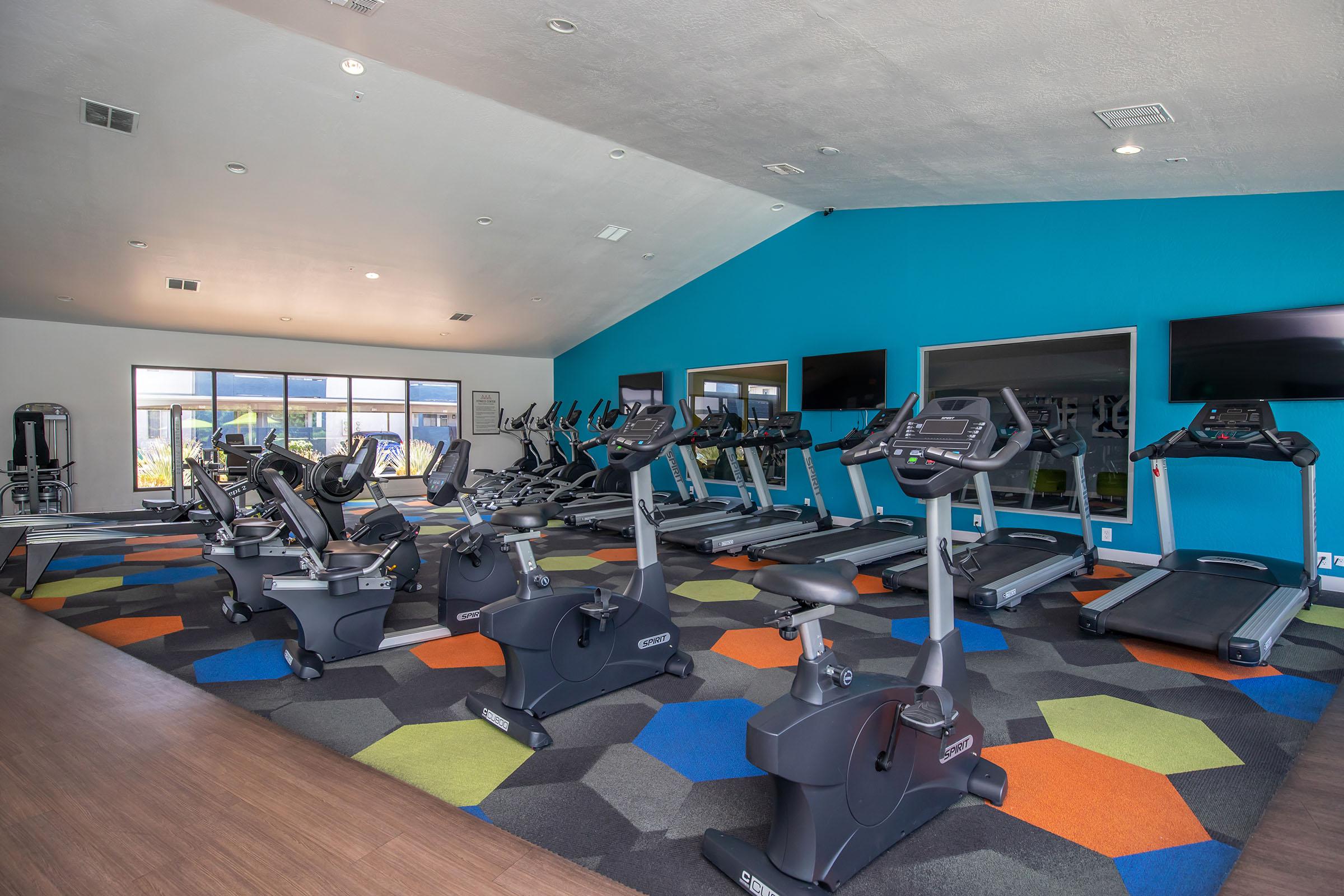 Rise at the District apartments indoor fitness center facility with workout machines and flat screen TVs