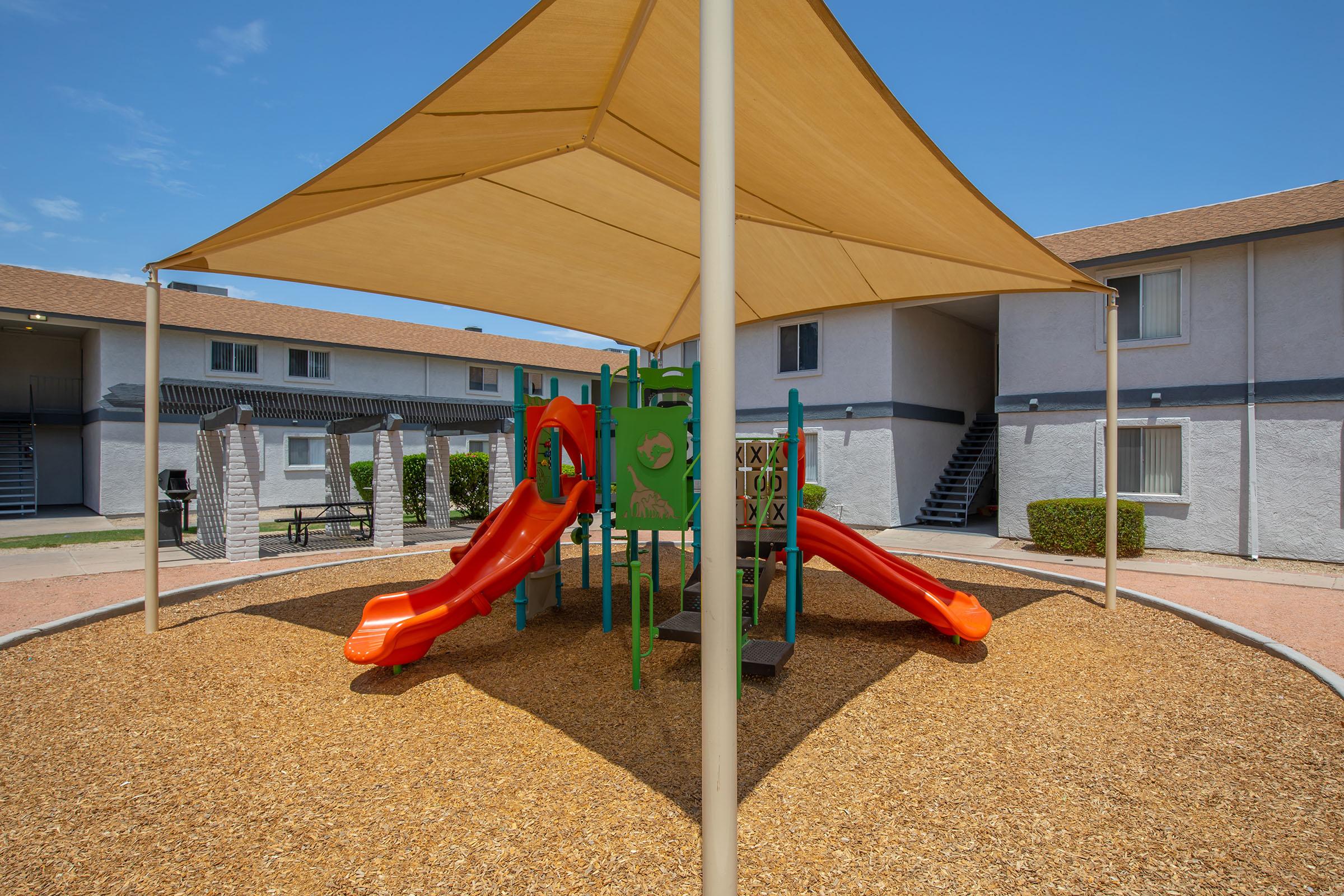 Rise at the District apartments outdoor playground set with large orange slides and sunshade covering
