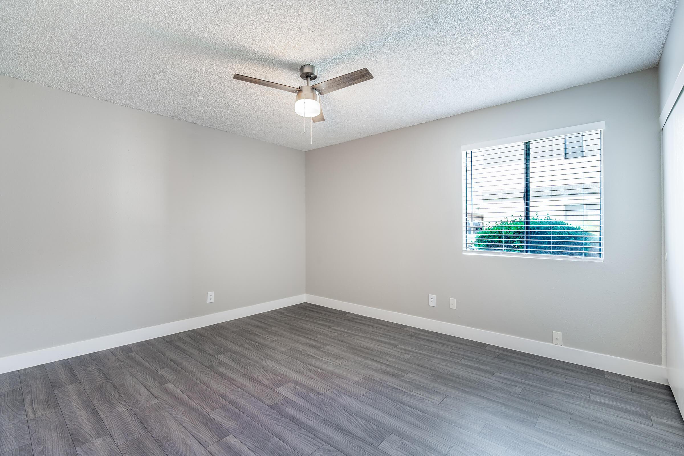 Open bright bedroom with large window and ceiling fan 