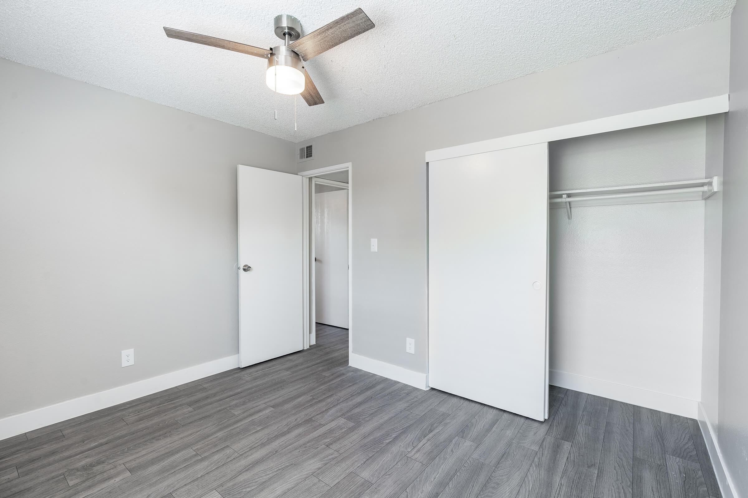 Modern spacious bedroom with sliding door closet, entryway, and ceiling fan