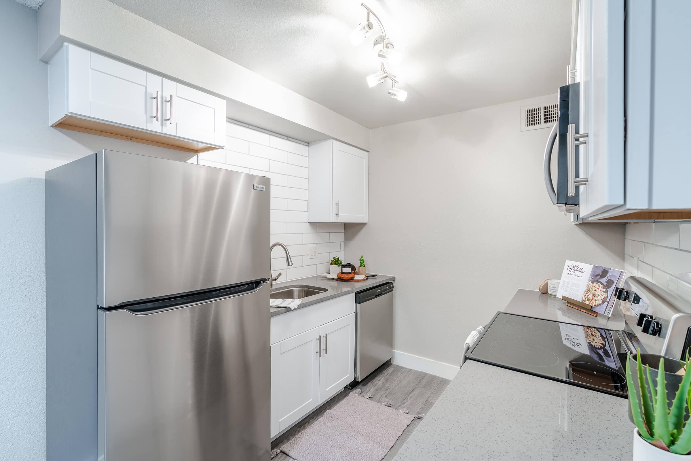 Galley way kitchen with white cabinets, white subway tile backsplash, and stainless steel appliances