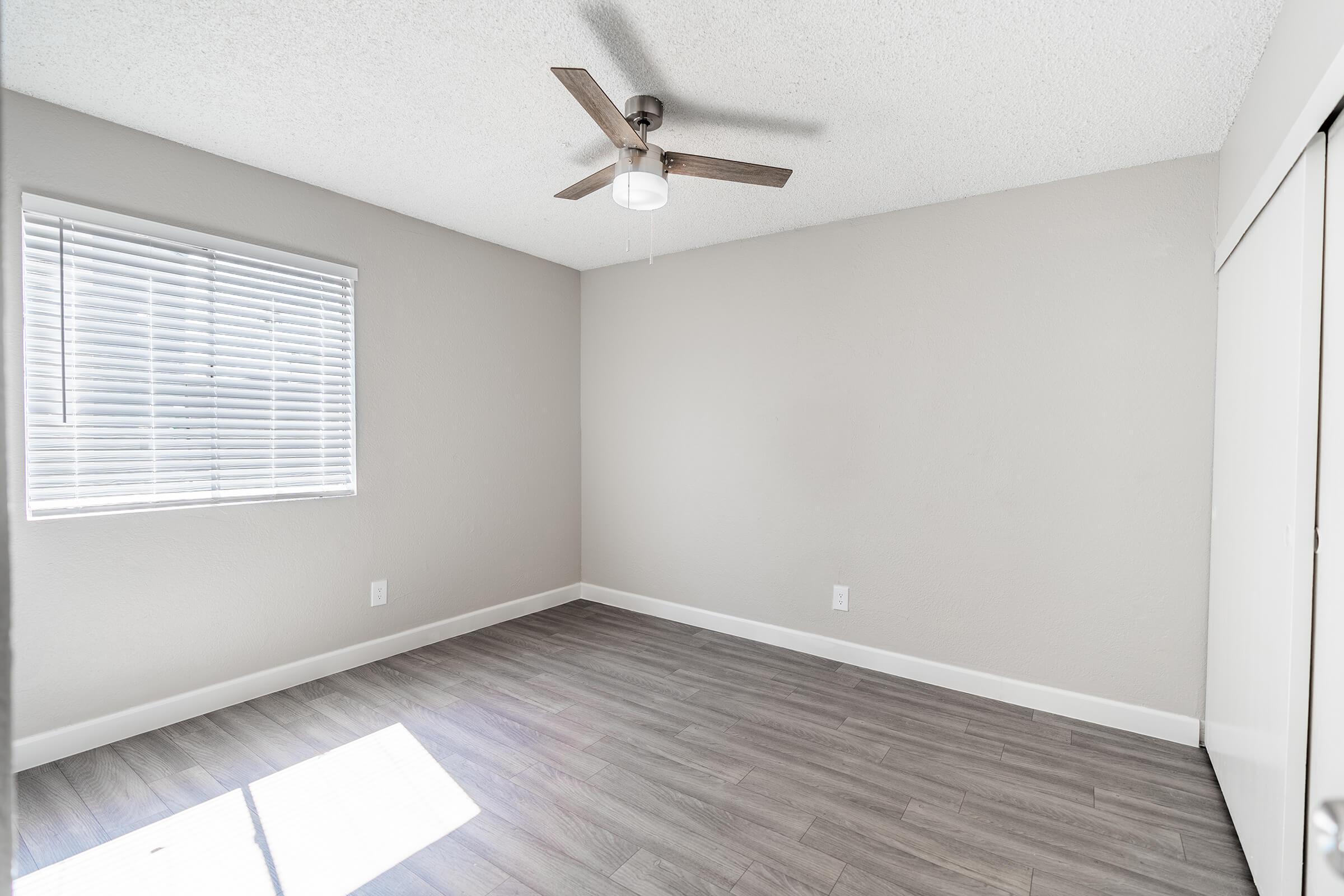 Open spacious bedroom with ceiling fan and large window