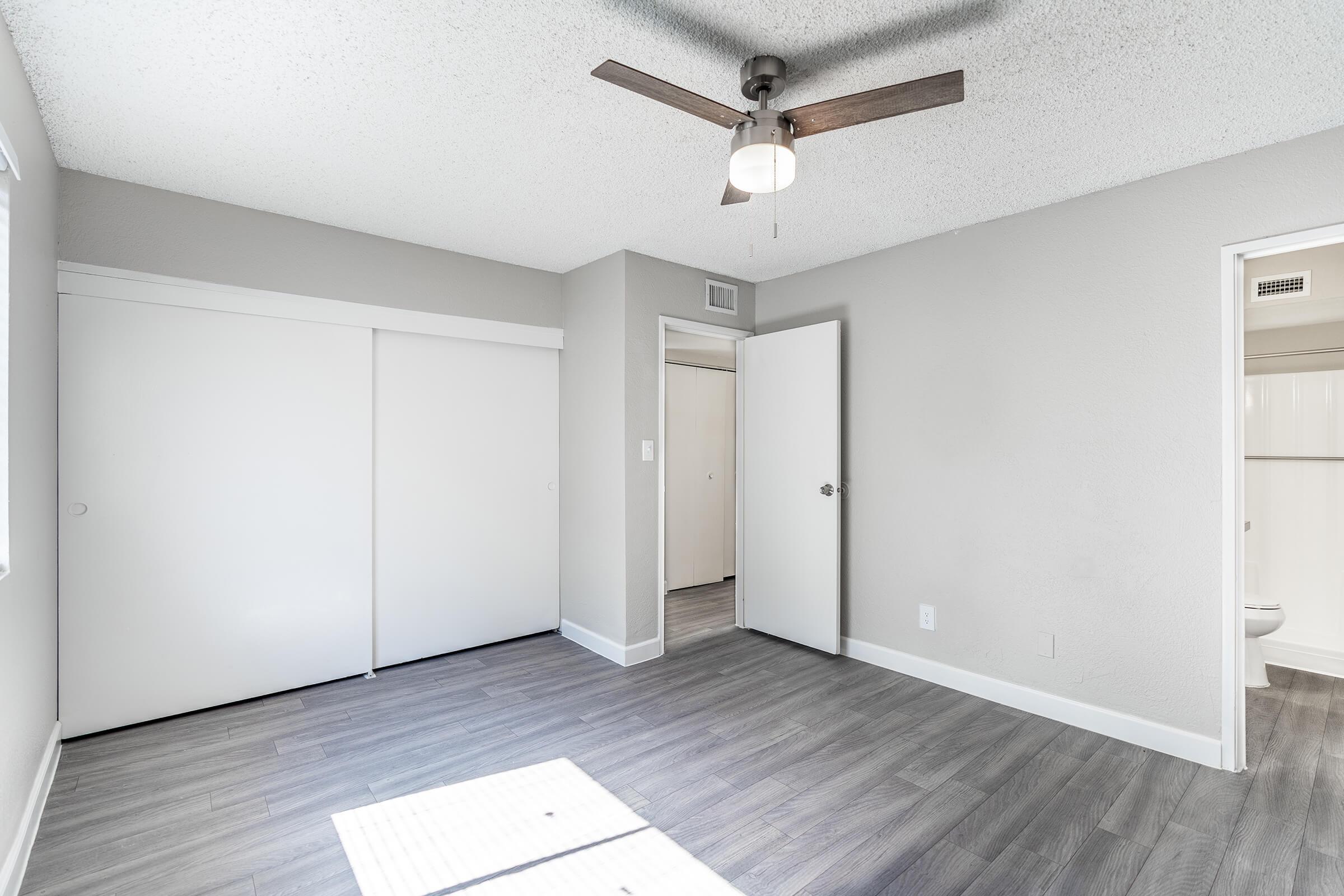 Modern renovated bedroom with white sliding door closet, ceiling fan, and attached bathroom