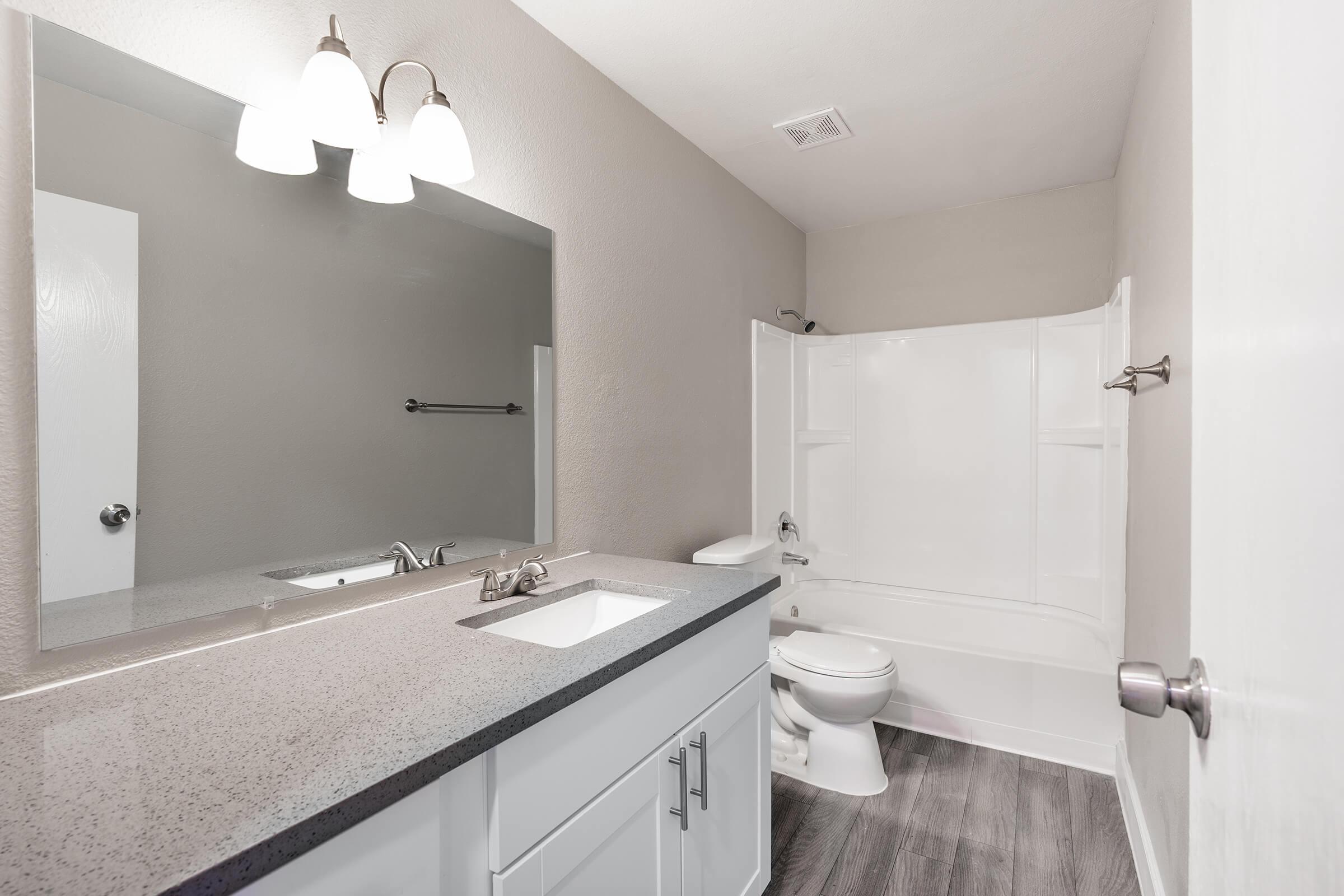 Bright renovated bathroom with quartz countertops and a large mirror