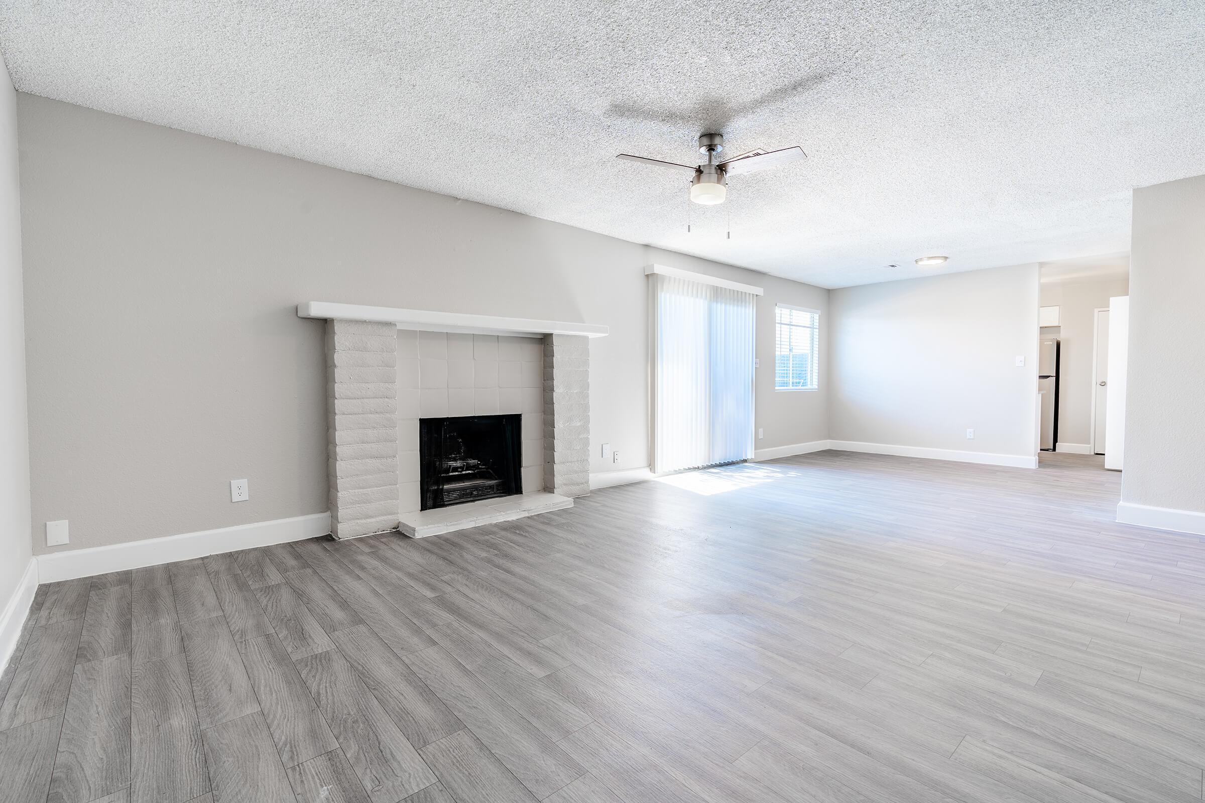 Open modern living room with brick fireplace and glass sliding doors leading to a patio