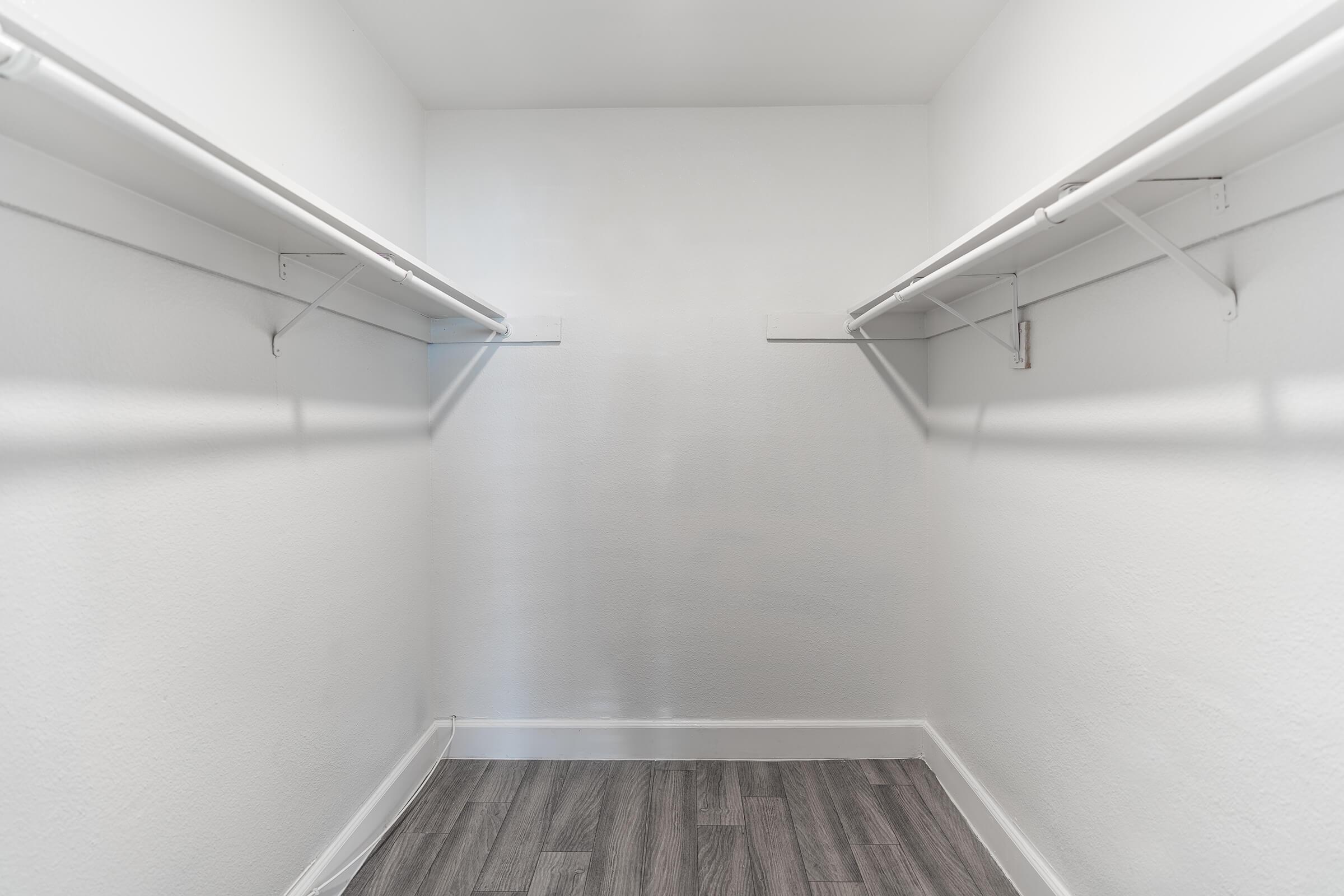 Walk in closet with large white shelves on each side