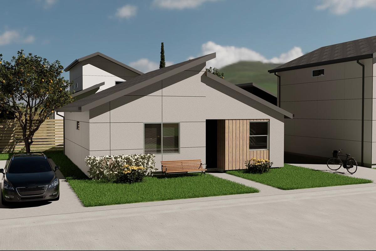 Modern single-story house with a flat roof, featuring a wooden front door and a small porch with a bench. The yard has manicured grass and shrubs, a parked car in the driveway, and a bicycle next to the house. In the background, there are additional buildings and trees under a blue sky.
