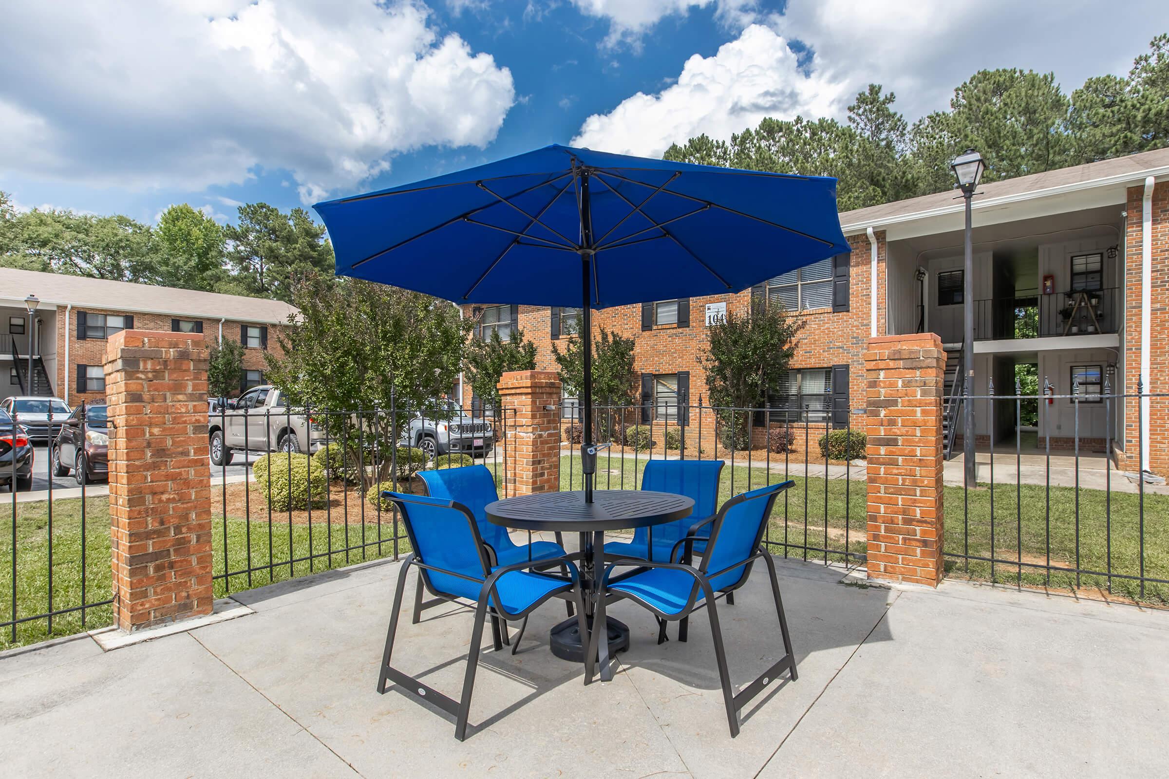 a chair sitting in front of a building with a blue umbrella