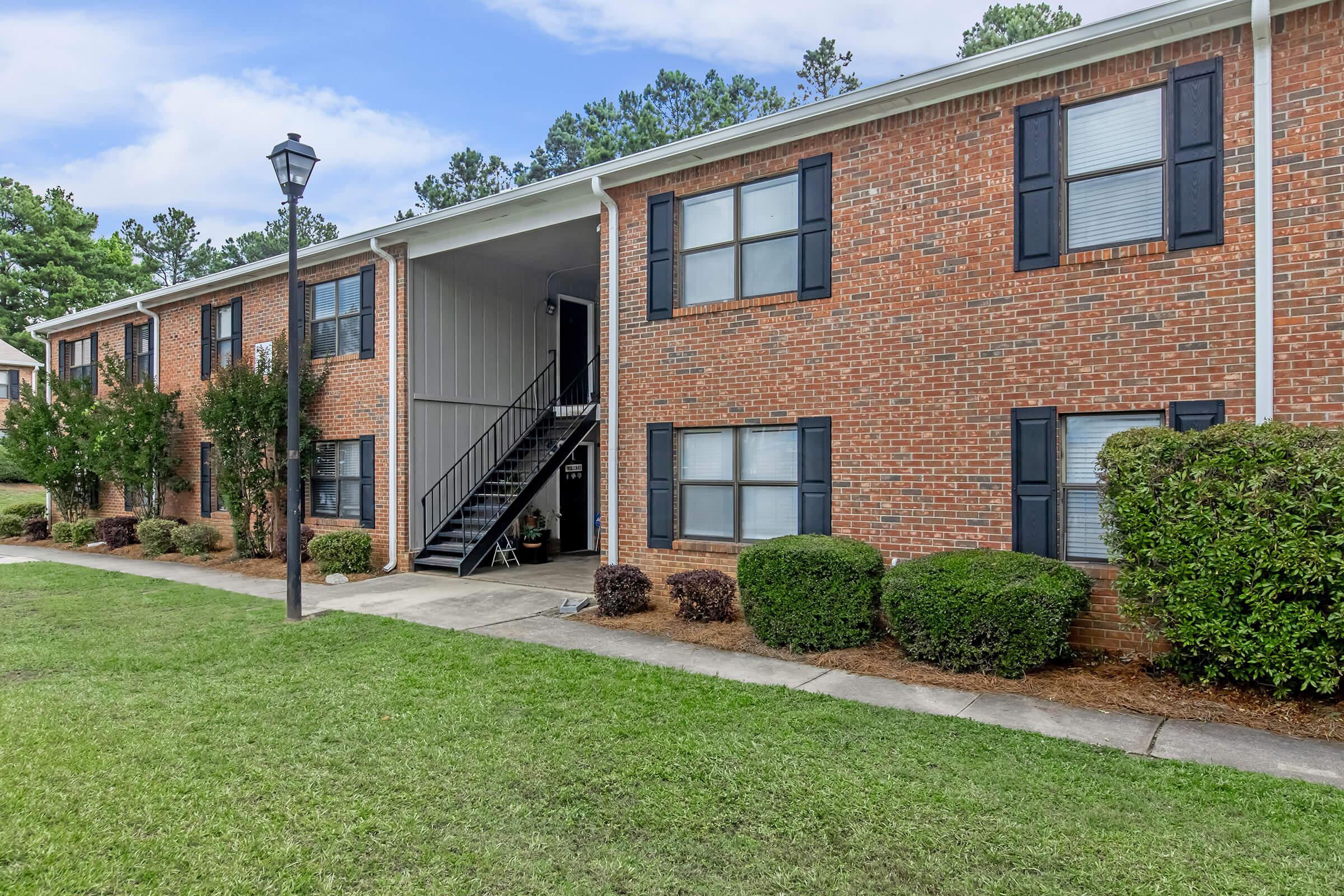 a large brick building with grass in front of a house