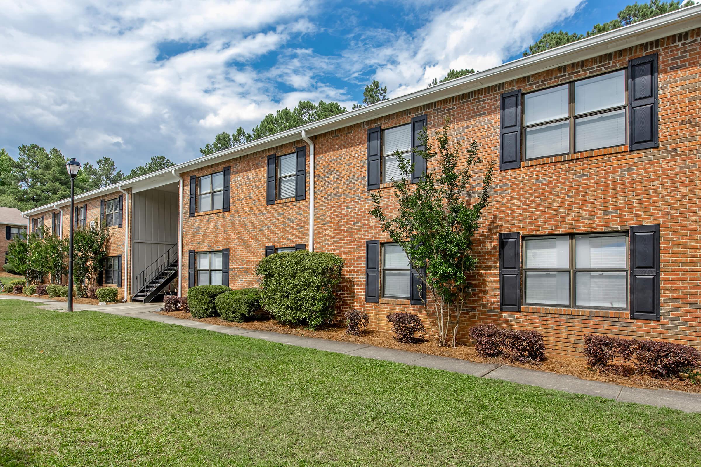 a large brick building with grass in front of a house