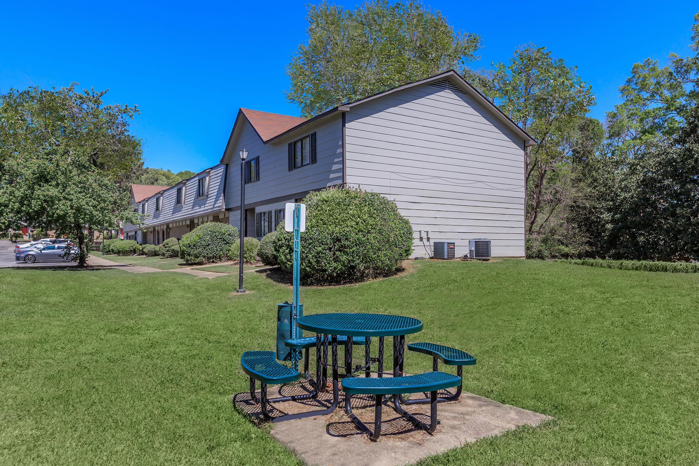 a green park bench sitting in front of a house