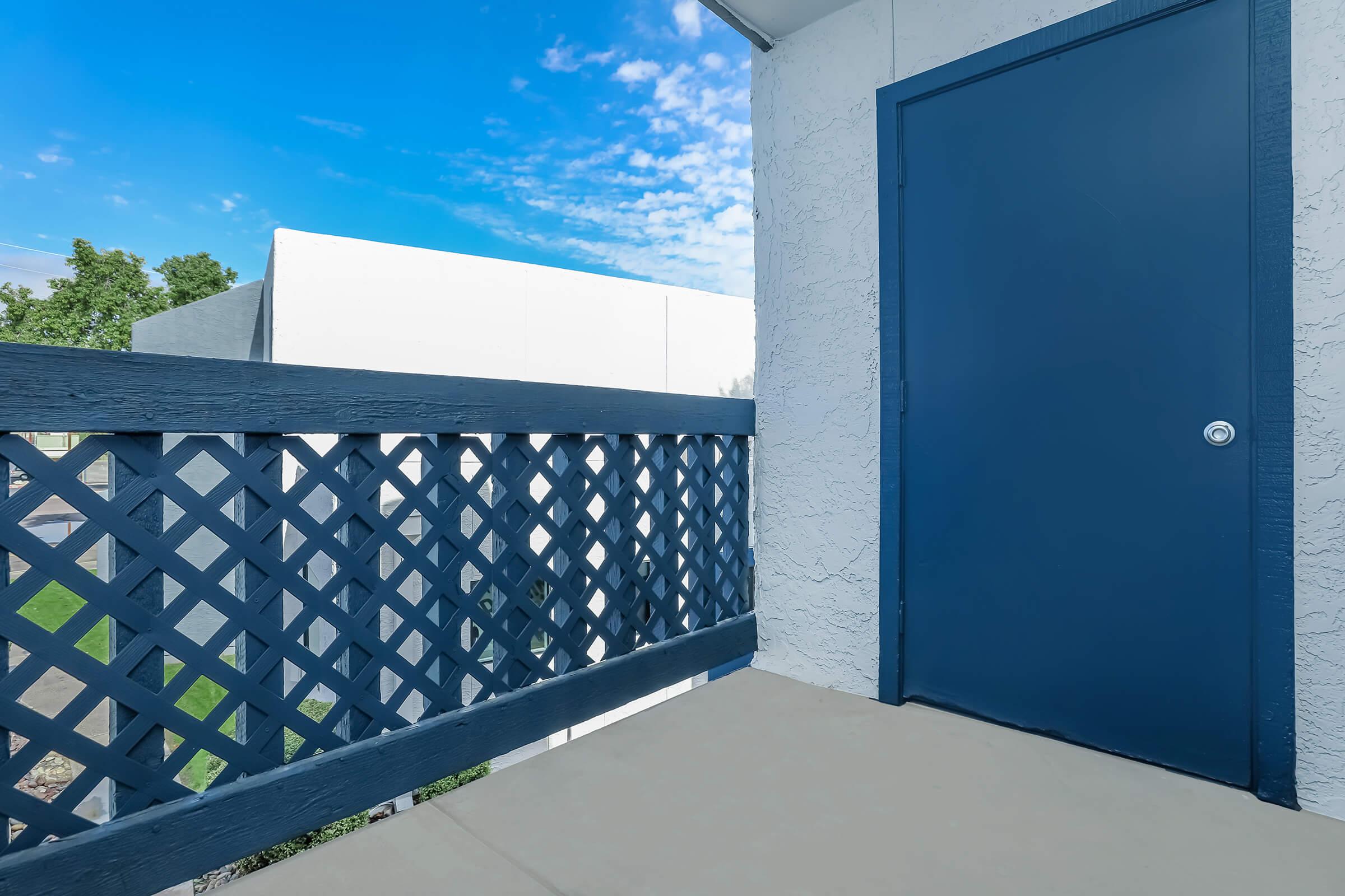 A balcony with a blue railing and storage at Rise at the Meadows in Glendale, AZ.