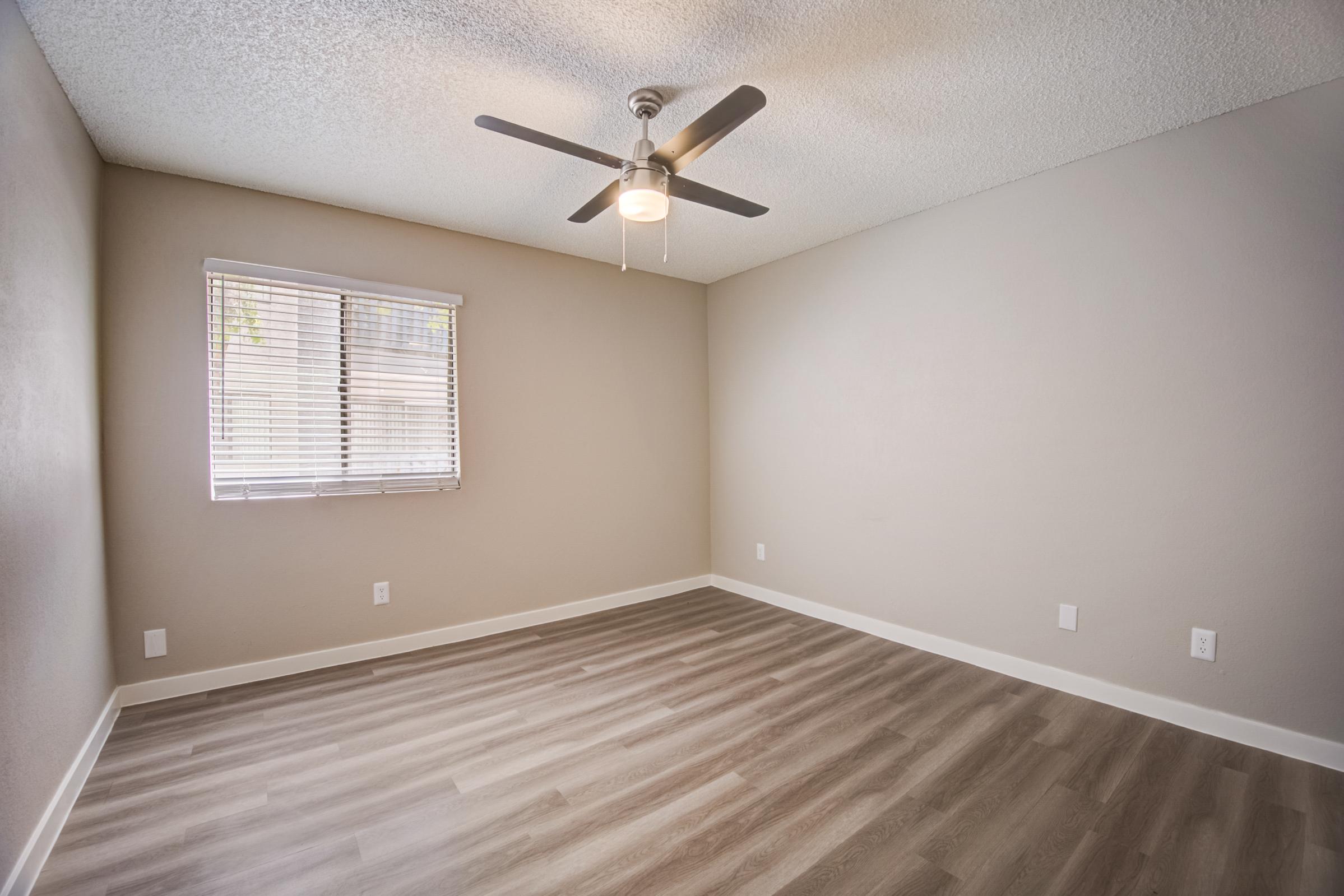 A bedroom at Rise at the Meadows with wood-style flooring and a ceiling fan.