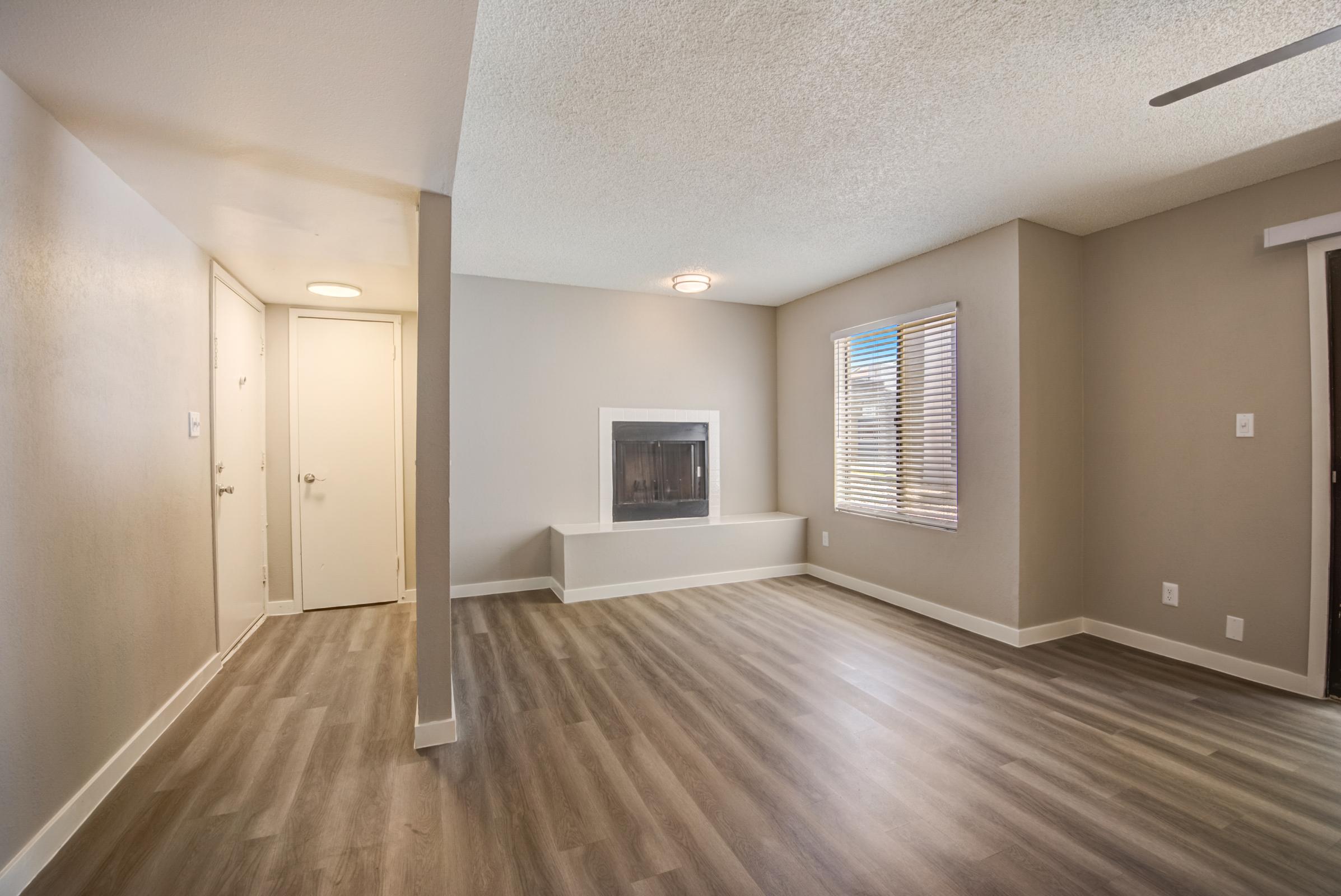 A hallway and living room with wood-style flooring at Rise at the Meadows.