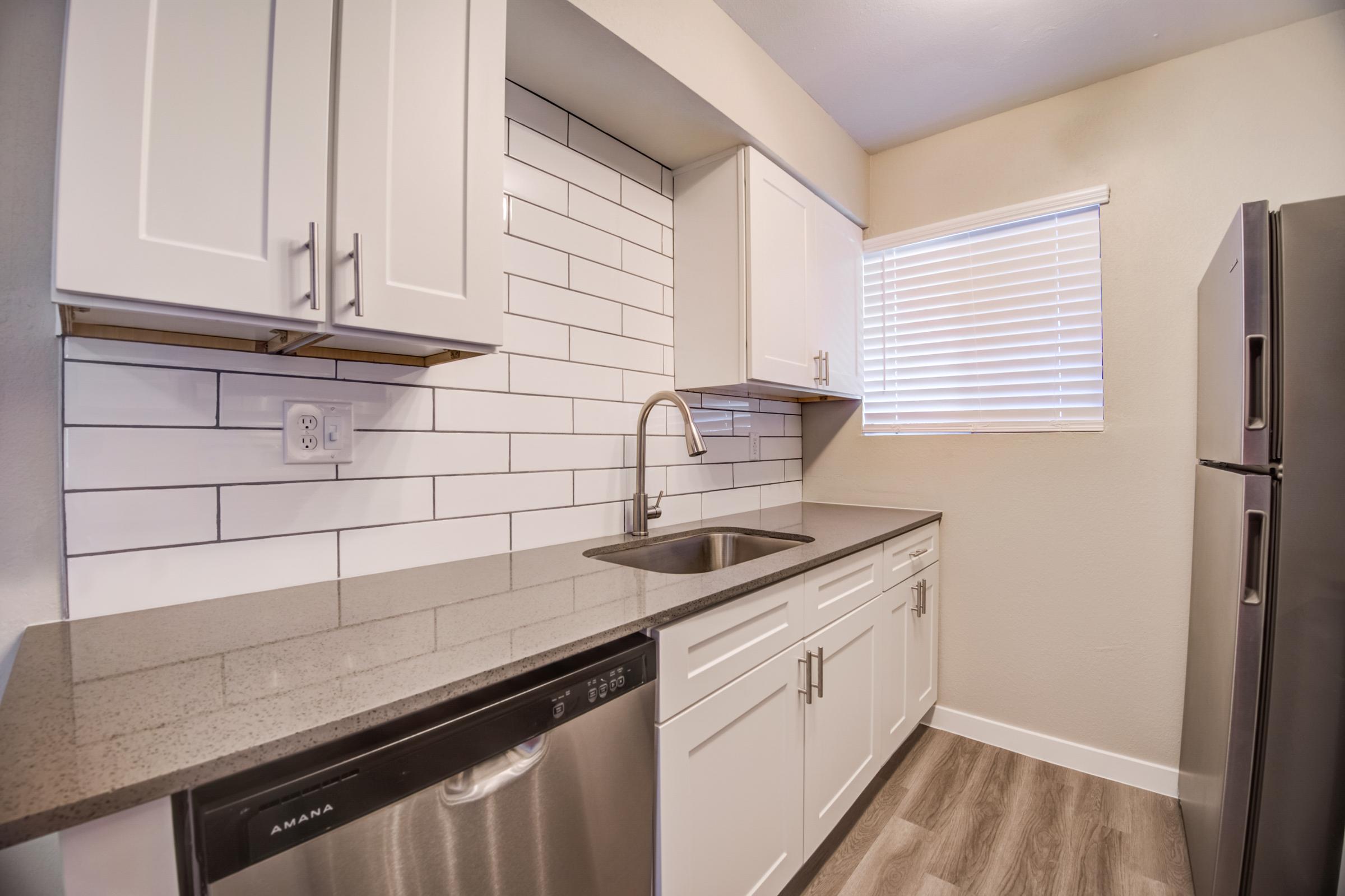 Rise at the Meadows remodeled kitchen with white cabinets and stainless steel appliances.