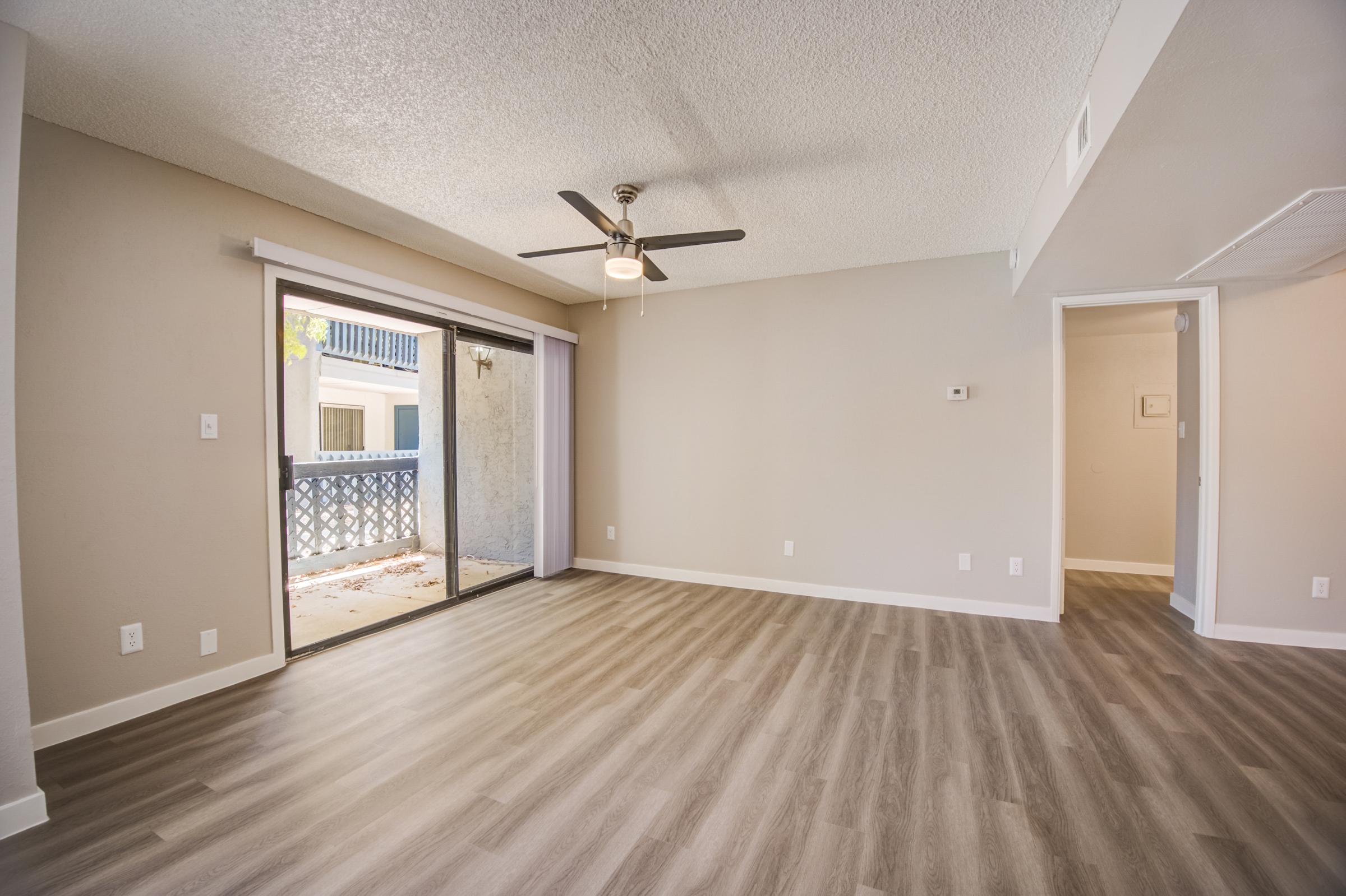 The apartment living room with wood-style flooring and a balcony at Rise at the Meadows.