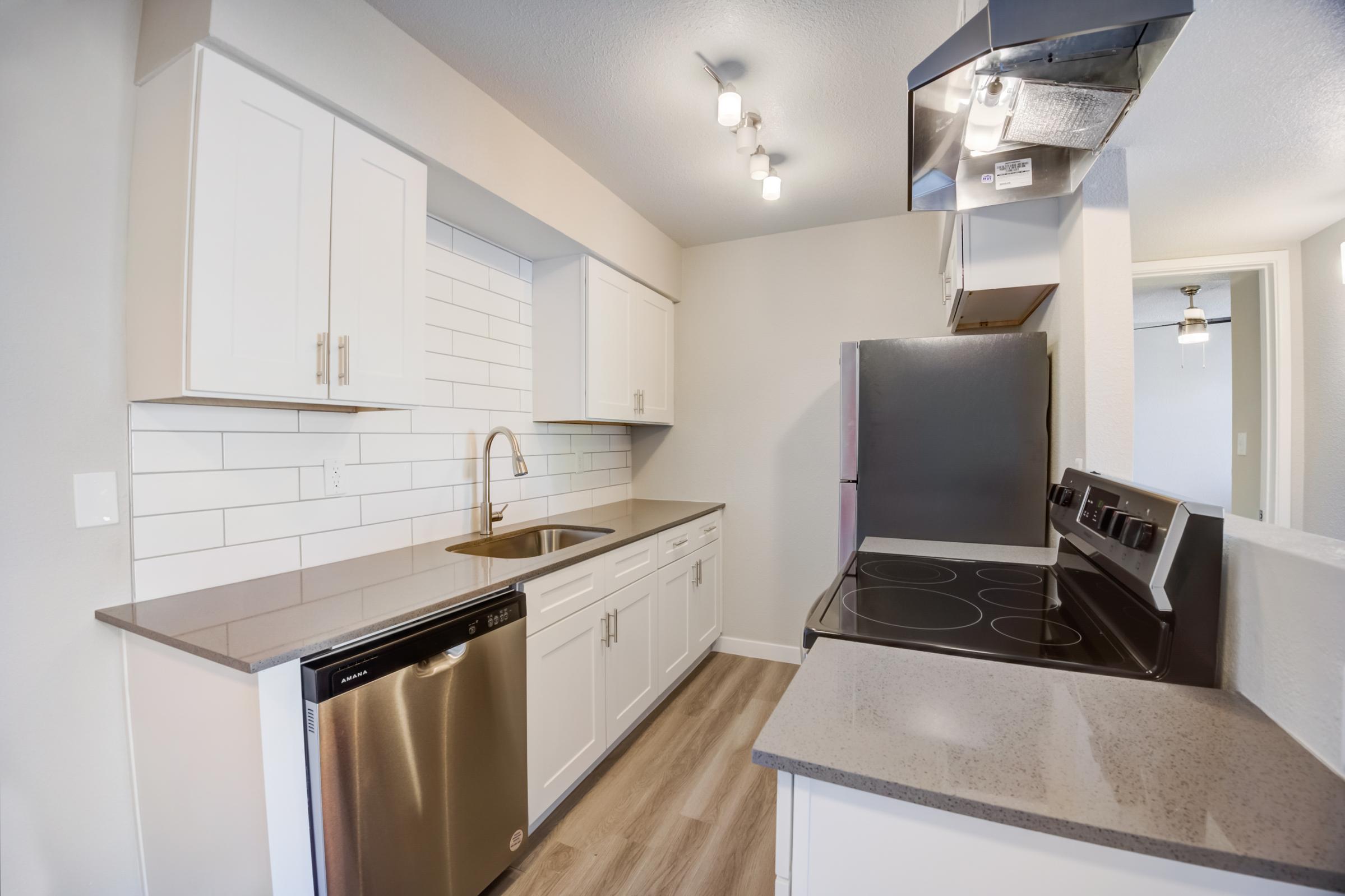 A Rise at the Meadows kitchen with white cabinets and stainless steel appliances.