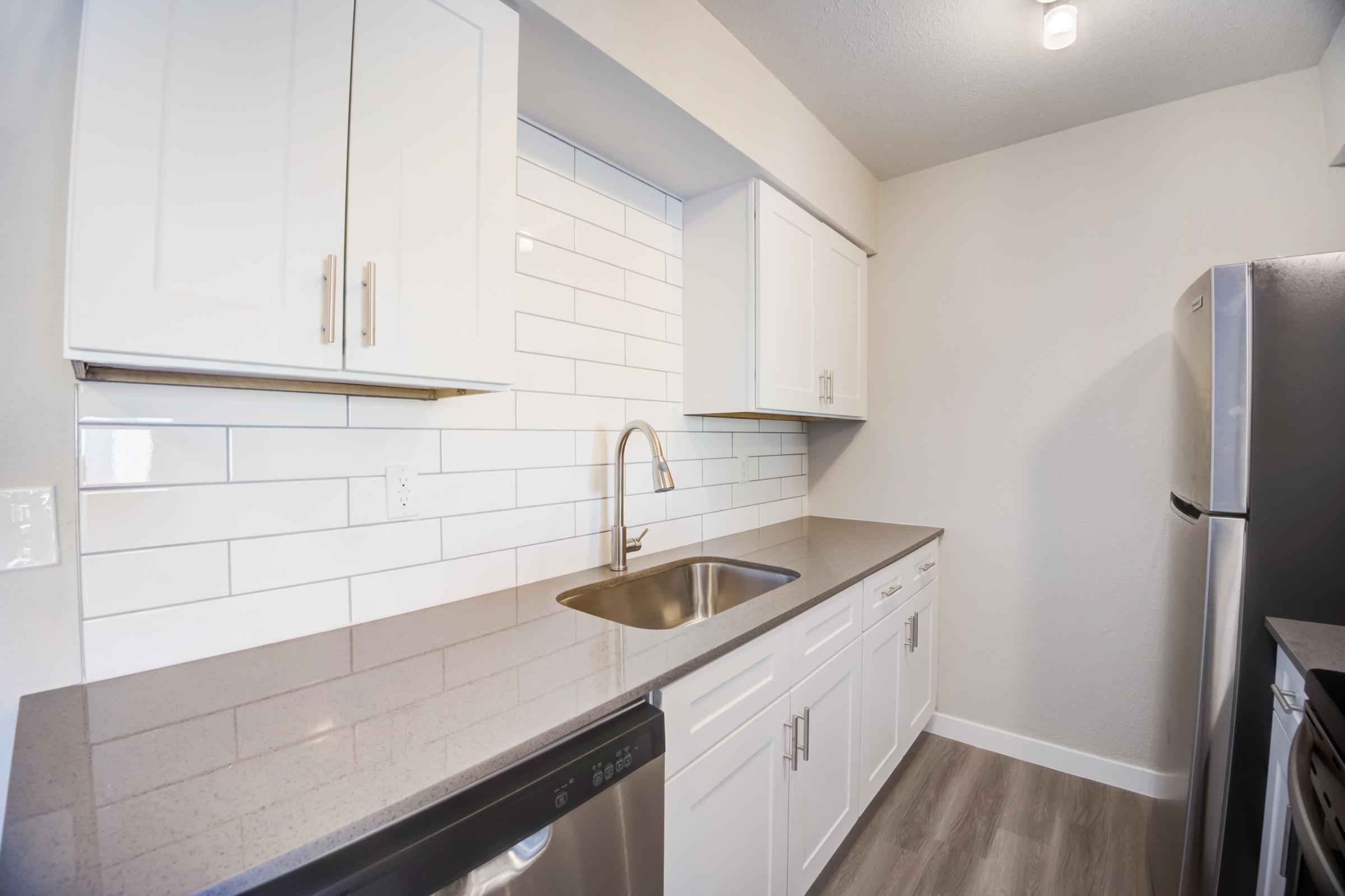 An apartment kitchen at Rise at the Meadows with a white backsplash and stainless steel appliances.