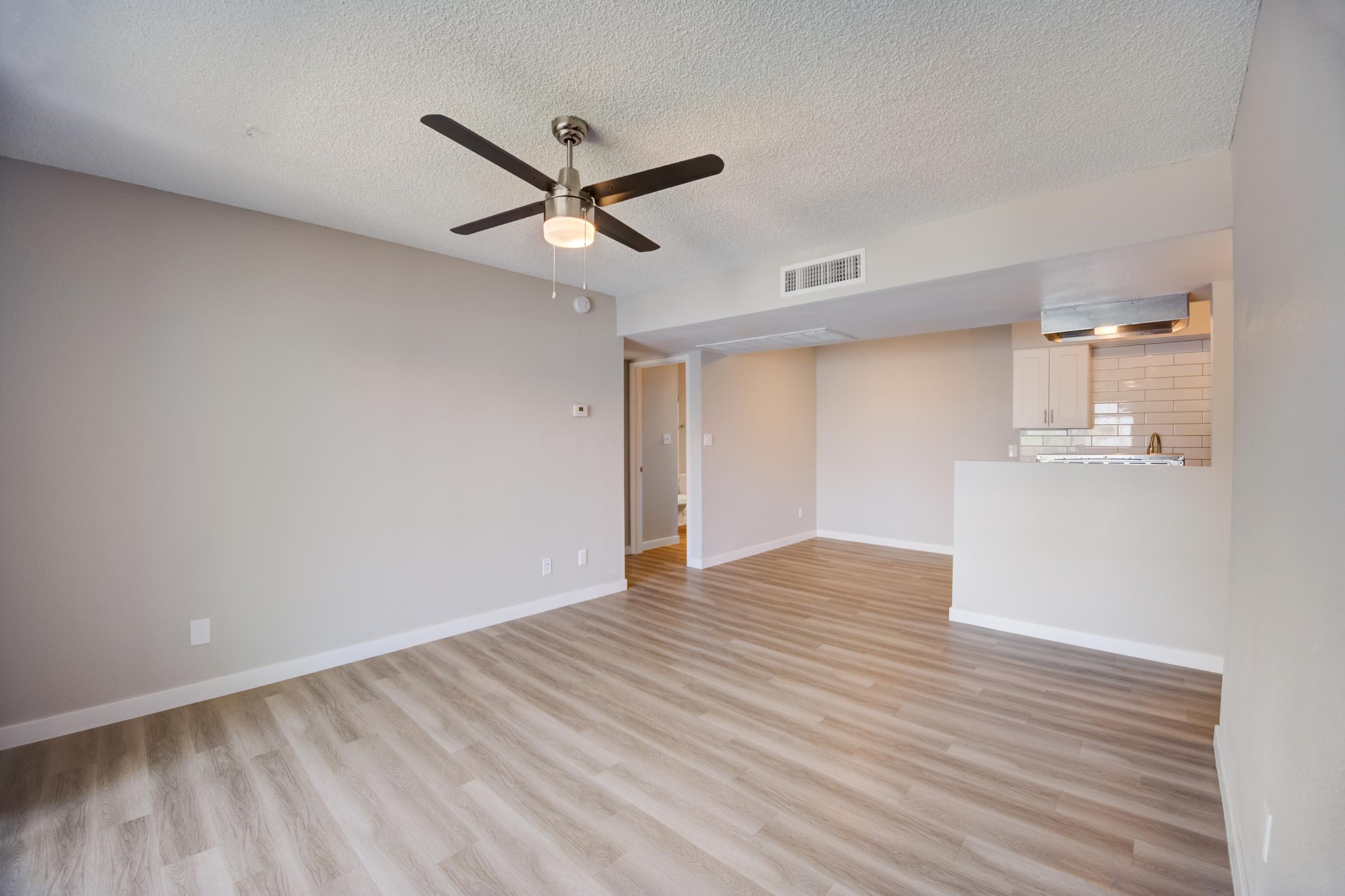 An apartment living room with a ceiling fan, dining area and kitchen at Rise at the Meadows.
