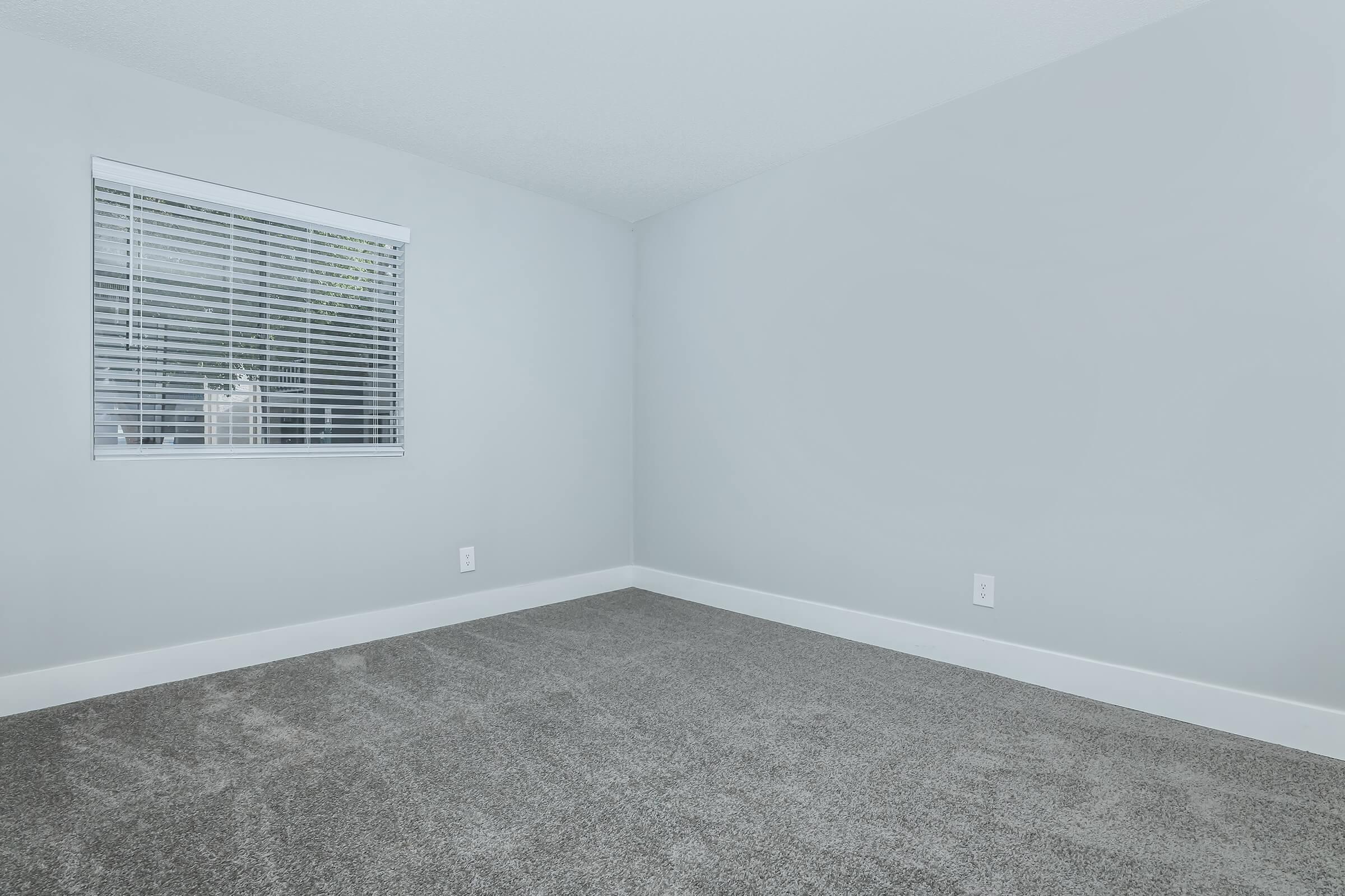 A carpeted room with a window at Rise at the Meadows in Glendale, AZ.