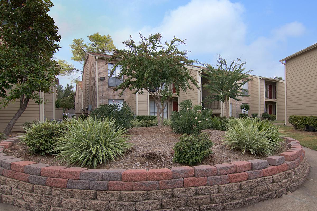 a house with bushes in front of a brick building