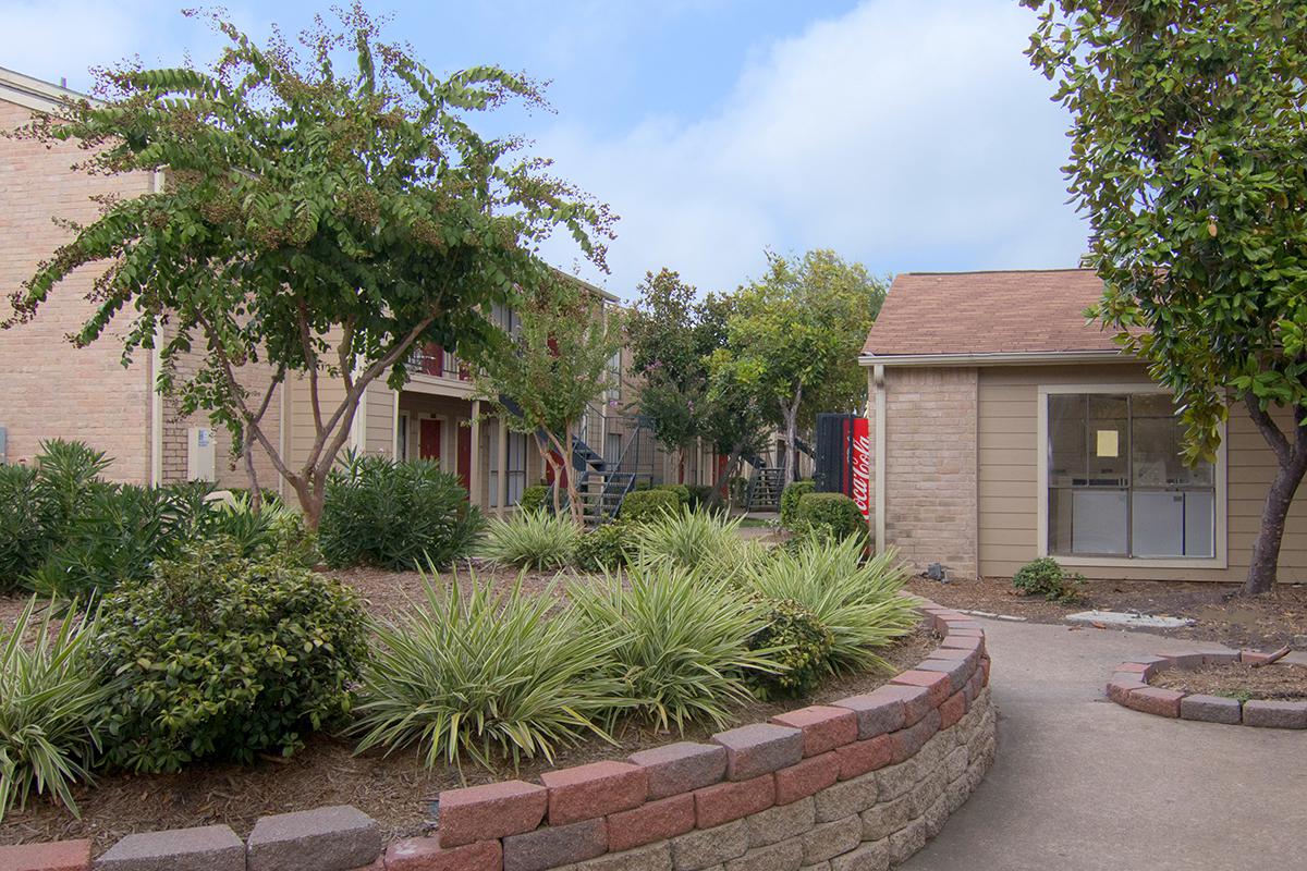 a house with bushes in front of a brick building