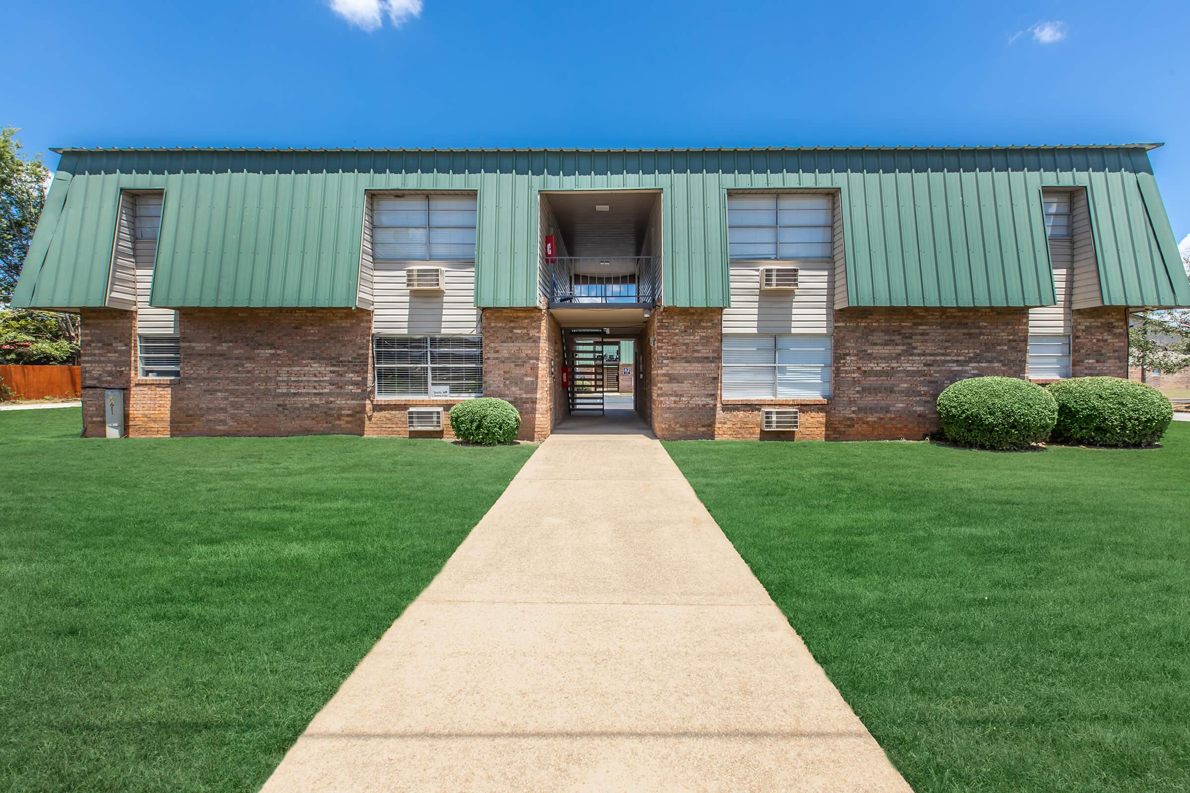 a large brick building with green grass