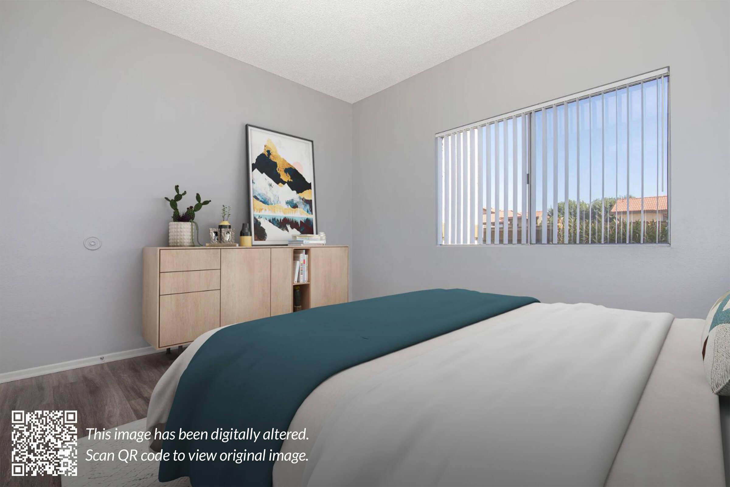 A neatly arranged bedroom featuring a bed with a teal blanket, a wooden side table, and a decorative piece on the wall. A window with vertical blinds allows natural light to illuminate the room, while a small plant is placed on the side table. A QR code indicates the image has been digitally altered.