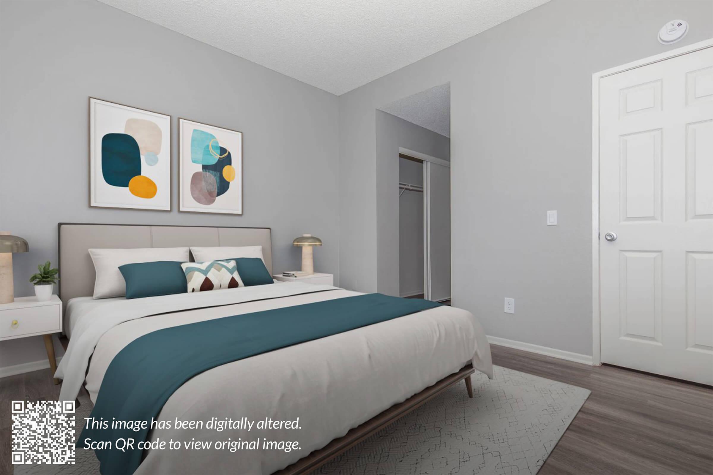 A modern bedroom featuring a bed with a teal and white bedspread, two bedside lamps, and framed abstract art on the wall. The room has light gray walls, a patterned rug, and a white door. A closet door is visible in the background. A QR code is present for additional information.