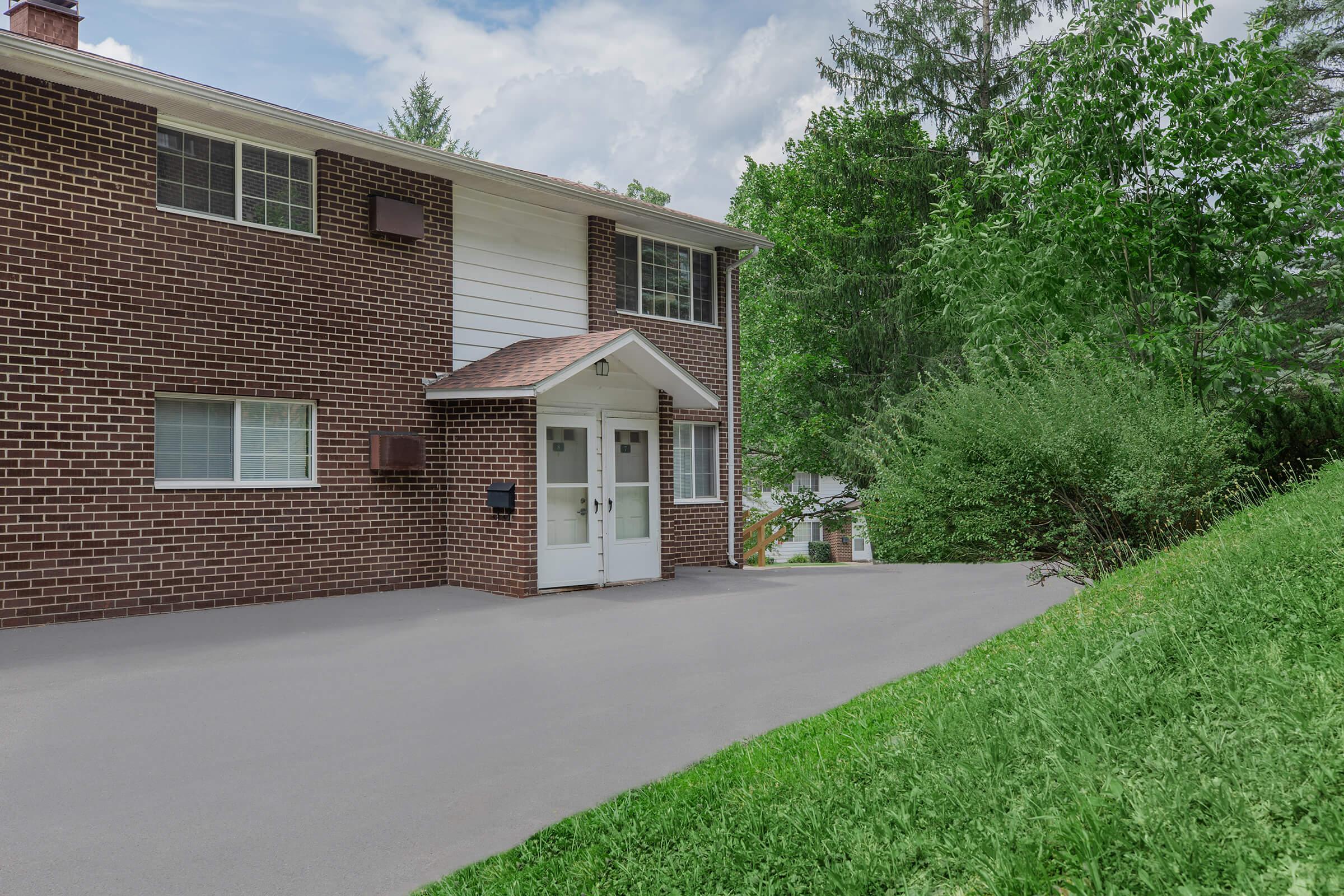 a large brick building with grass in front of a house